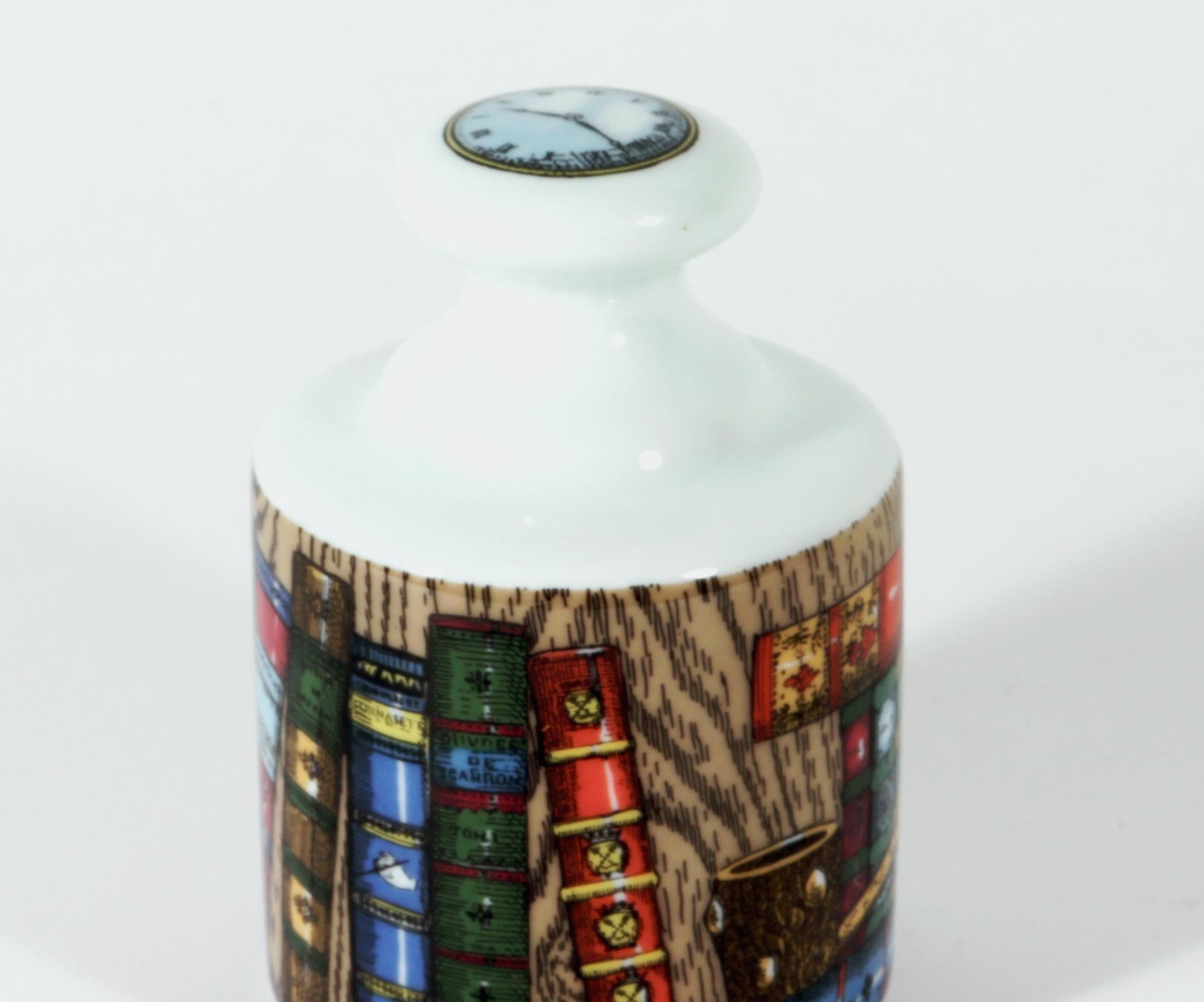 Fermacarte in porcellana Rosenthal Fornasetti,
Rosenthal Classic,
DeKor Libreria Pattern, (Biblioteca),
1980s

Il fermacarte circolare in porcellana di Fornasetti presenta una scena continua di libri, un orologio da tasca, una chiave e un porta