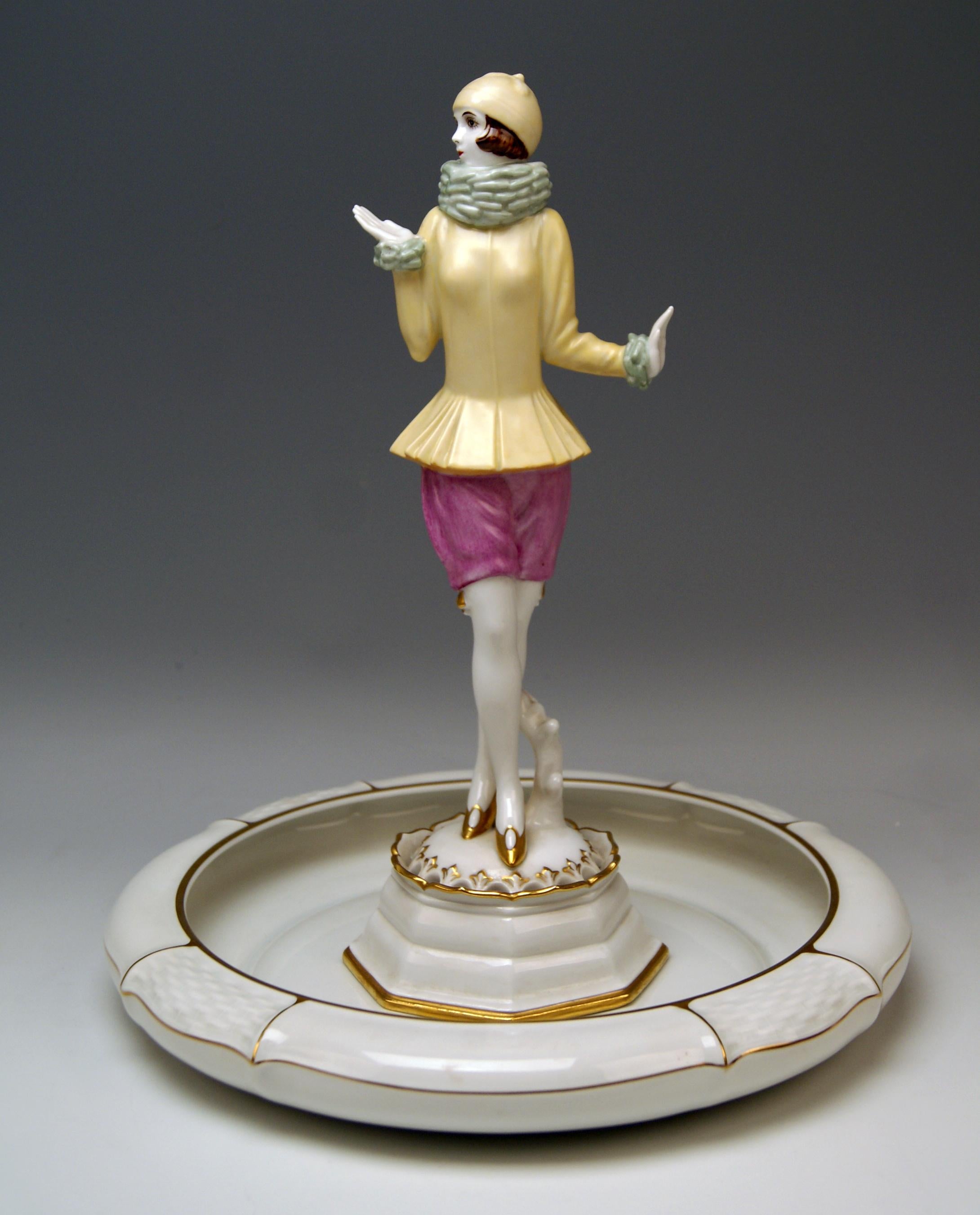 Lady Figurine 'YVONNE'
Slim lady wearing cap stands upright, clad in very special costume: Tight yellow jacket and woollen scarf covering woman's neck and short lilac trousers (hot pants). The woman is wearing golden high heels, having her legs