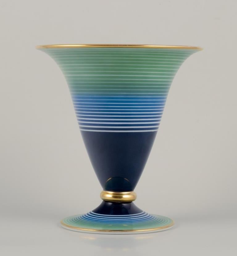 Rosenthal, Germania.
Grande vaso a tromba in porcellana Art Déco. 
Decorato a mano in smalto blu e verde con un disegno a righe e un bordo dorato. Modello raro.
Circa 1930.
Contrassegnato.
Condizioni perfette.
Dimensioni: H. H. 19,8 cm x P. 18,5 cm.