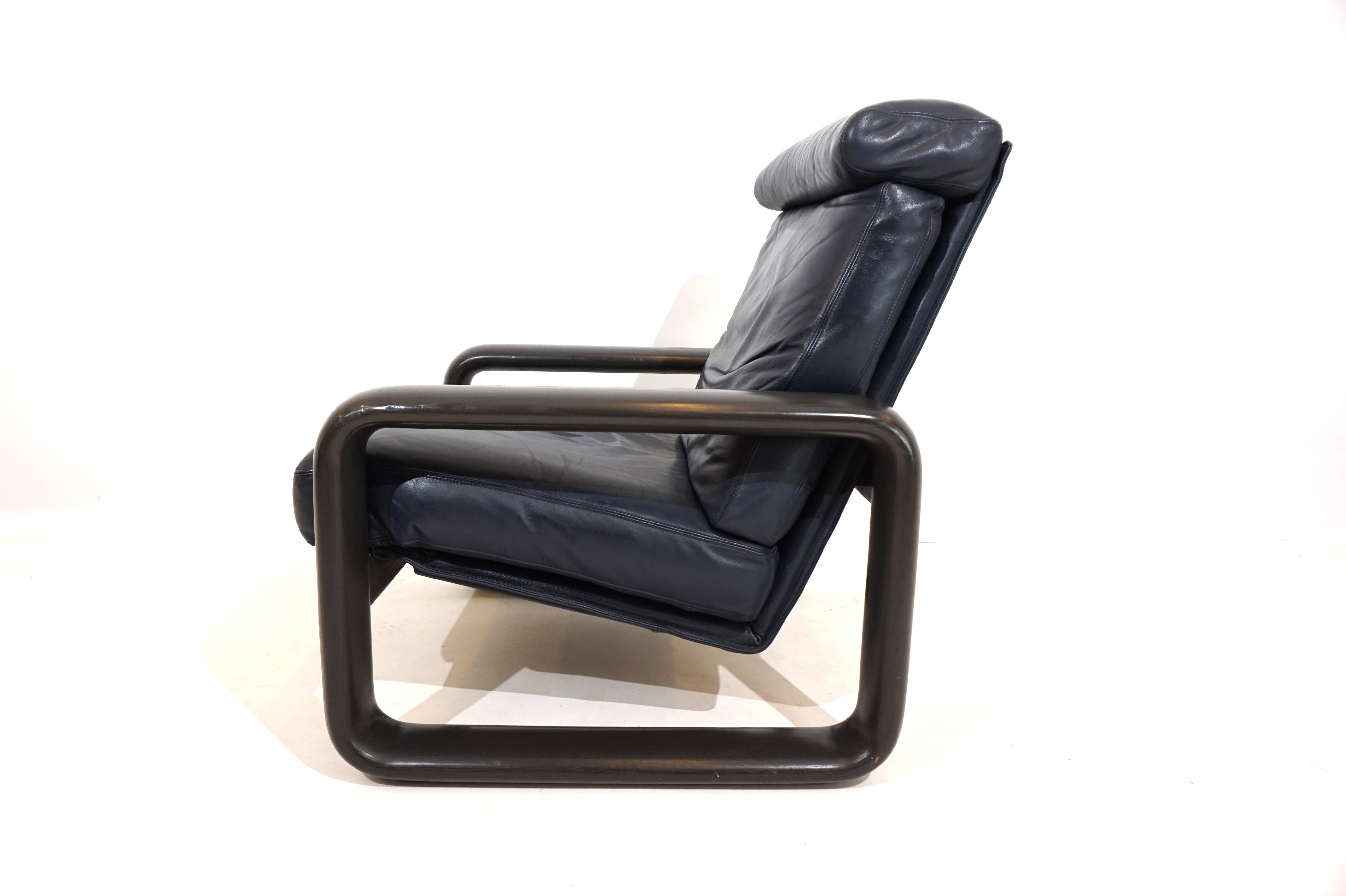 Le fauteuil en cuir, d'un ton bleu/noir exceptionnel, avec un cadre en bois de couleur anthracite, est en excellent état. Le cuir ne présente que des signes minimes d'usure sur l'assise, les dossiers en bois massif sont en parfait état. Le modèle