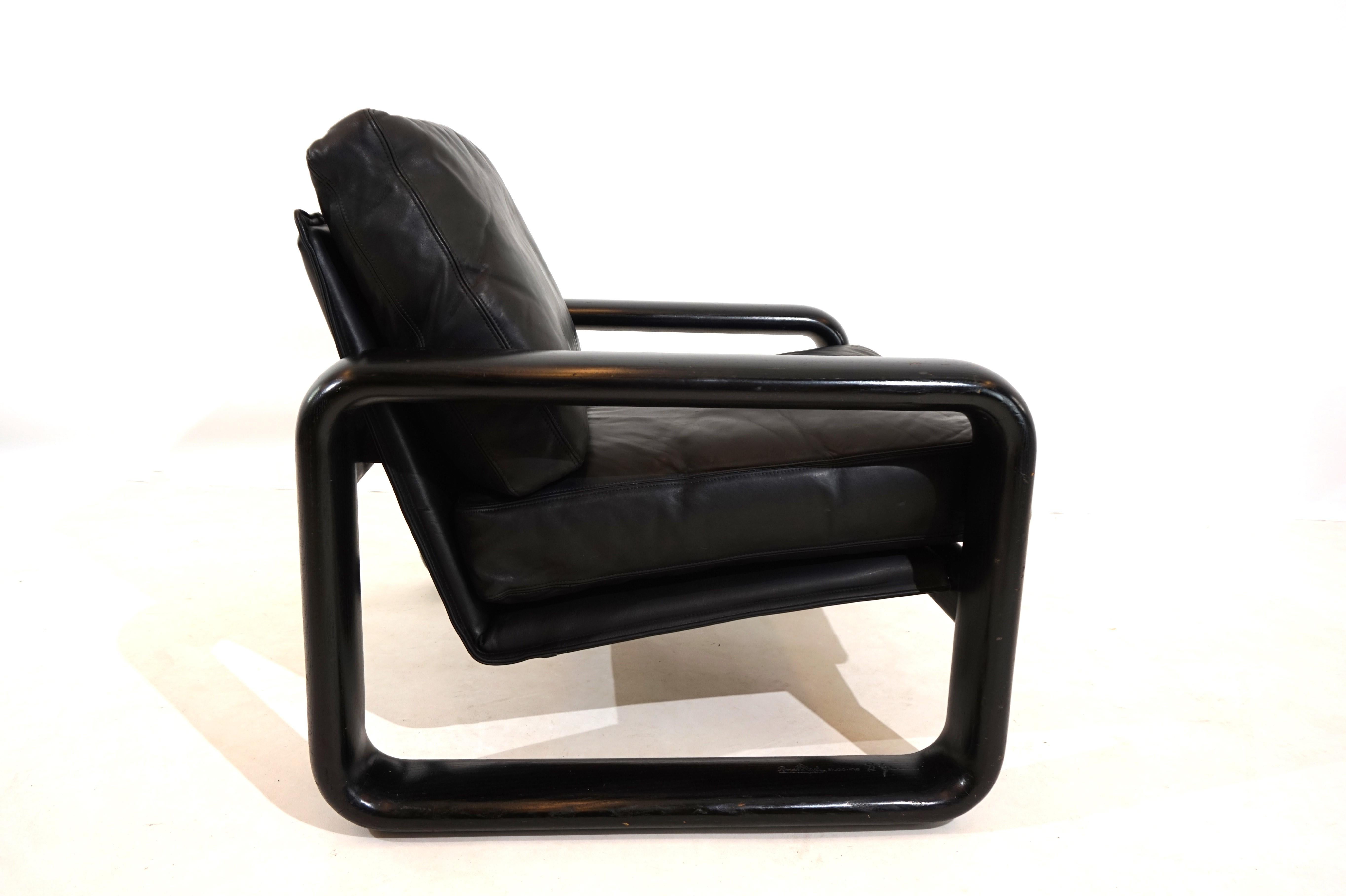 A Hombre leather armchair in the popular version with a black wooden frame and black leather in very good condition. The leather of the cushions and backrest shows hardly any signs of wear and is soft and supple. The solid wooden backrests have a