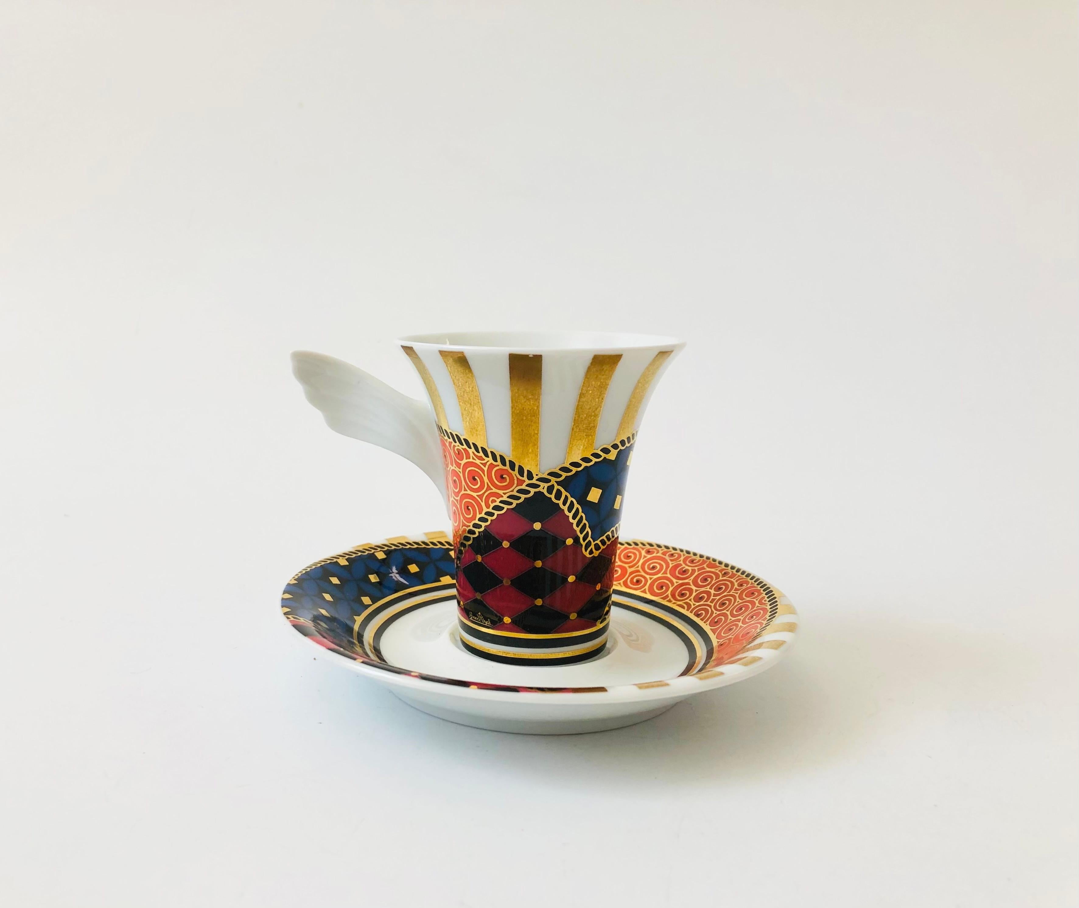 A vintage collectible porcelain espresso mug and saucer set from the Mythos line by Rosenthal, Germany. Signed by the designer, Yang, and numbered NR 4. Features an intricate matching design on the cup and saucer with a winged handle.