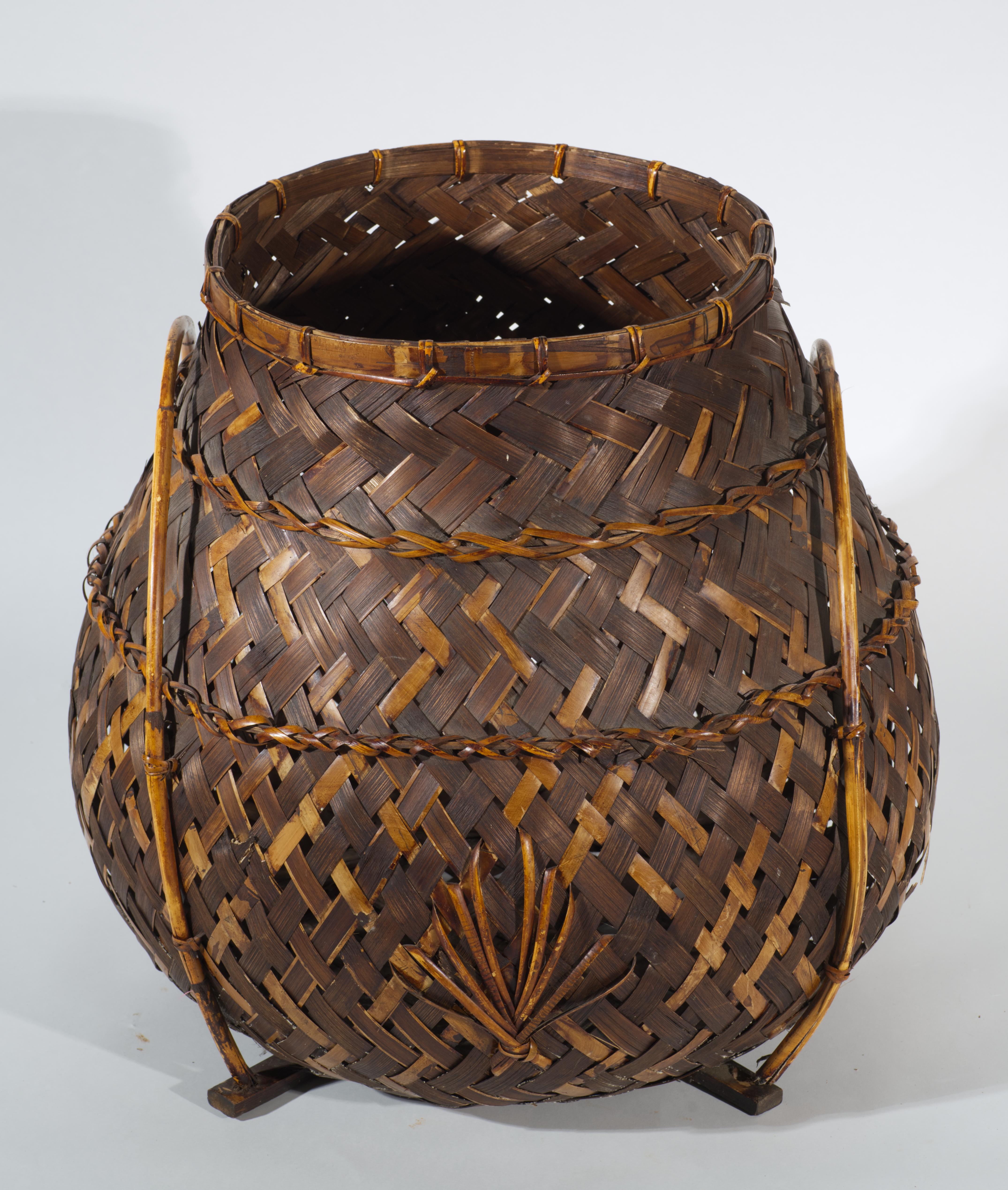 Vintage sculptural bamboo and rattan or wicker basket features an unusual form with a wide rounded base that tapers towards the opening. The body of the basket is hand woven with simple, but graphic weave that incorporates horizontal bands to