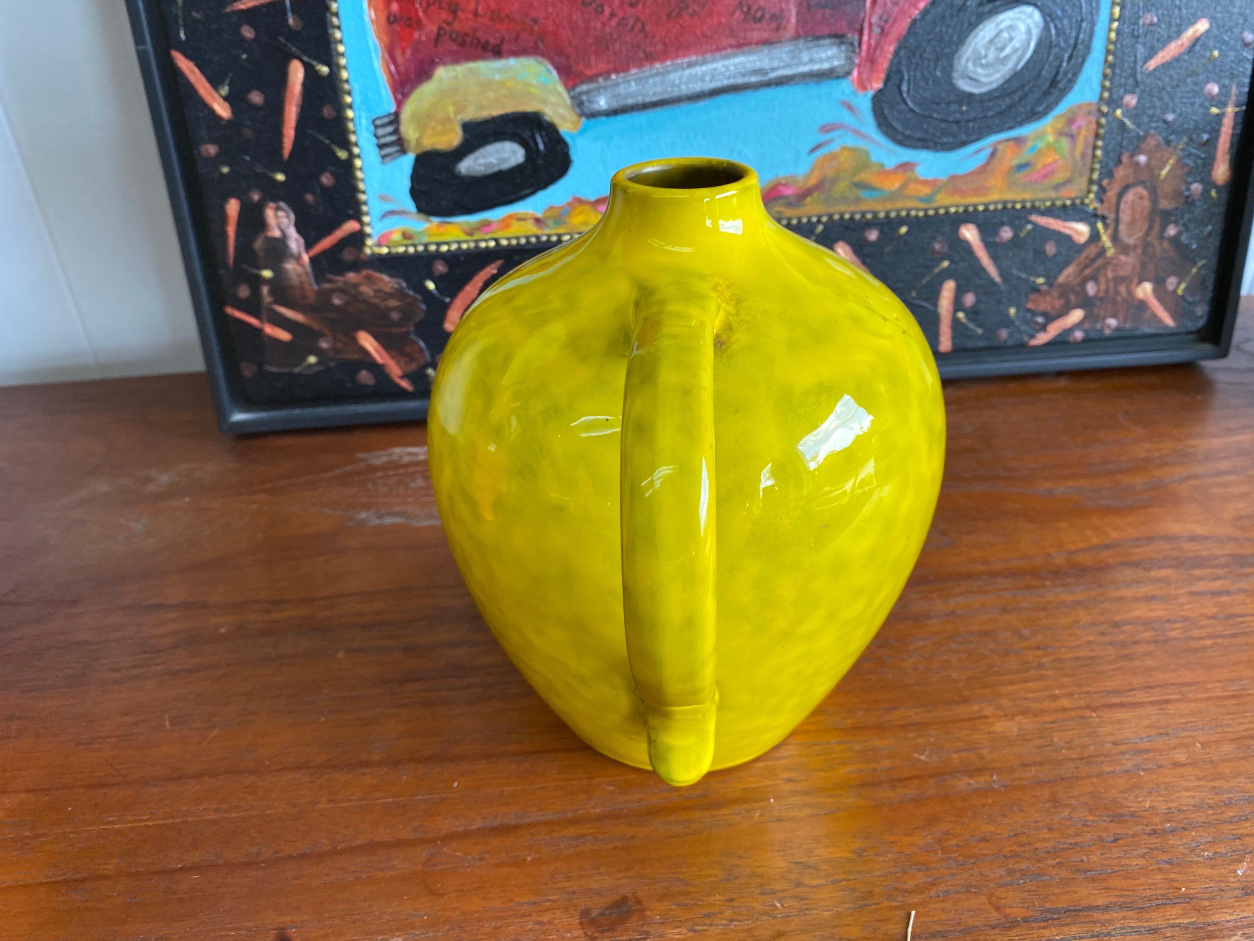 Made in Italy, this vibrant yellow Mid-Century Modern decorative ceramic vase designed by Rosenthal-Netter is in good condition. With a unique shape and bold yellow color, this vase / candle holder will brighten any space.