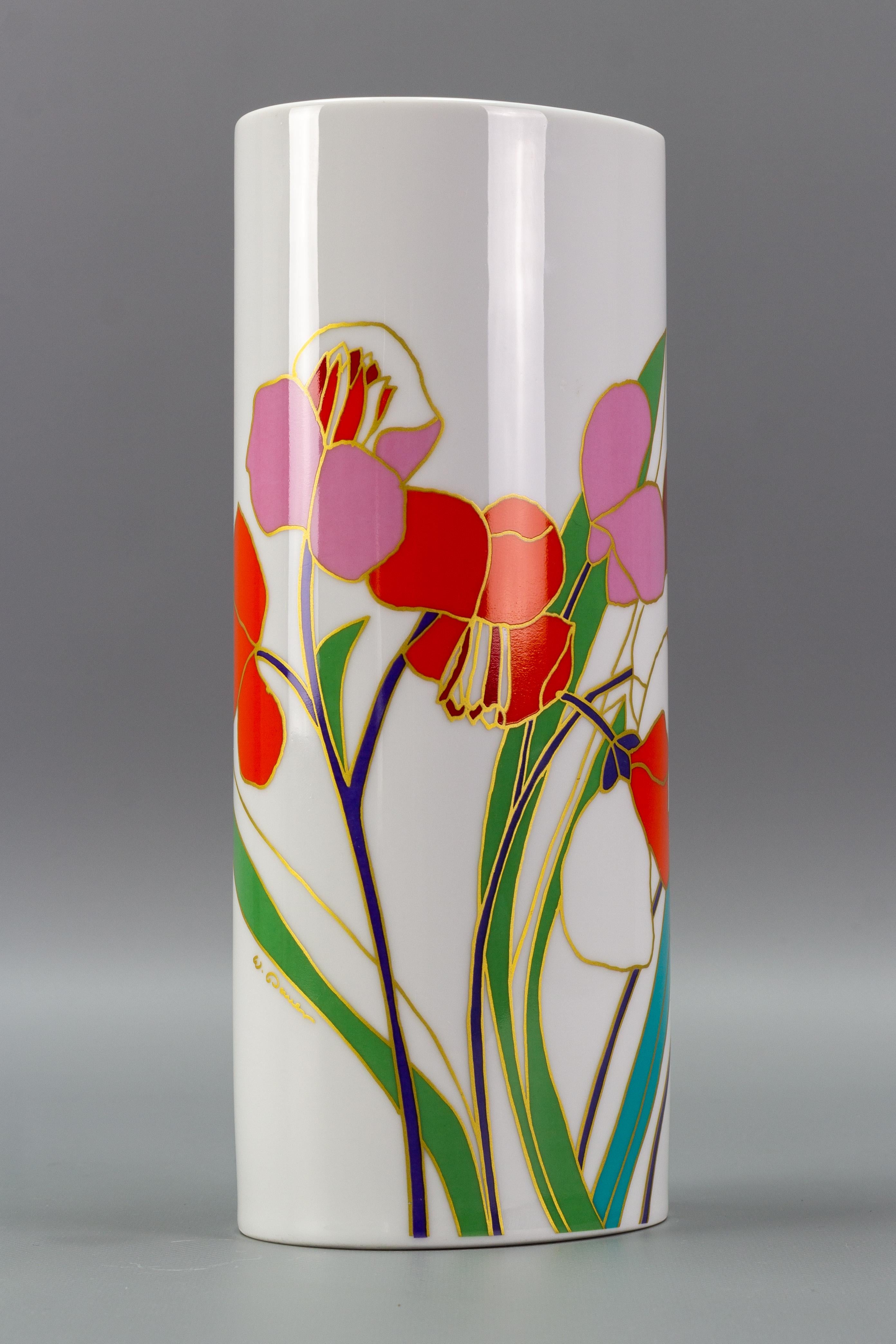 A hand-painted Rosenthal porcelain vase designed by Wolf Bauer, the Studio-Linie line, Germany, 1970s-1980s. 
The white porcelain vase is in a cylindrical form and is adorned with brightly colored flowers and leaves outlined in gold.
The vase is