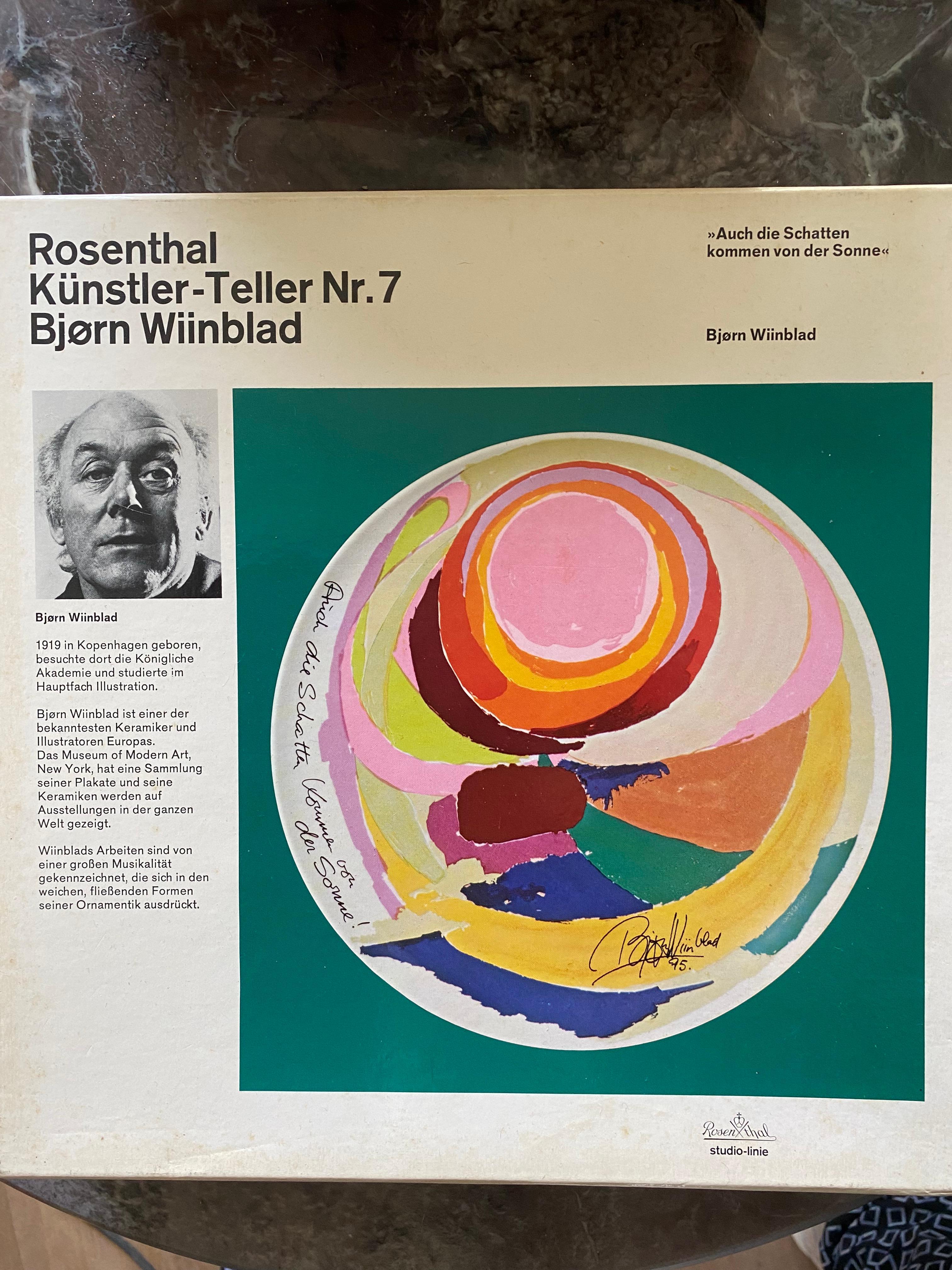 Stunning wall plaque by Bjorn
Wiinblad for Rosenthal. The  plaque was produced in 1975 in an edition of 5000, and this one is number 1328. 

The text on the plate is German ‘auch die Schatten kommen von der Sonne’ which can be translated as ‘also