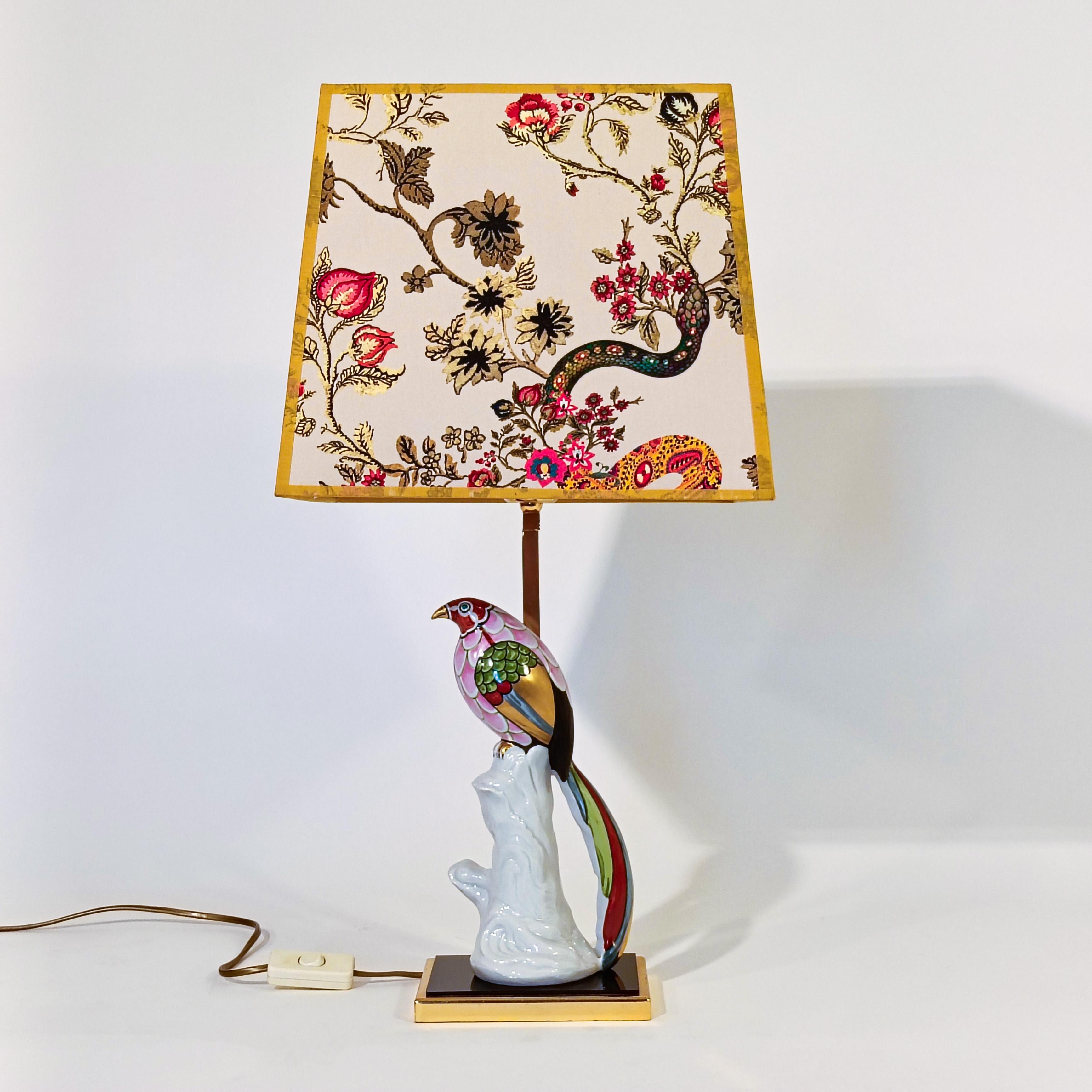 Porcelain table lamp by Studio-Line for Rosenthal, Germany, 1980s. Hand-painted porcelain piece representing a multicolored bird of paradise with golden details. Base and structure in golden chrome metal, with a black piece of acrylic. Original