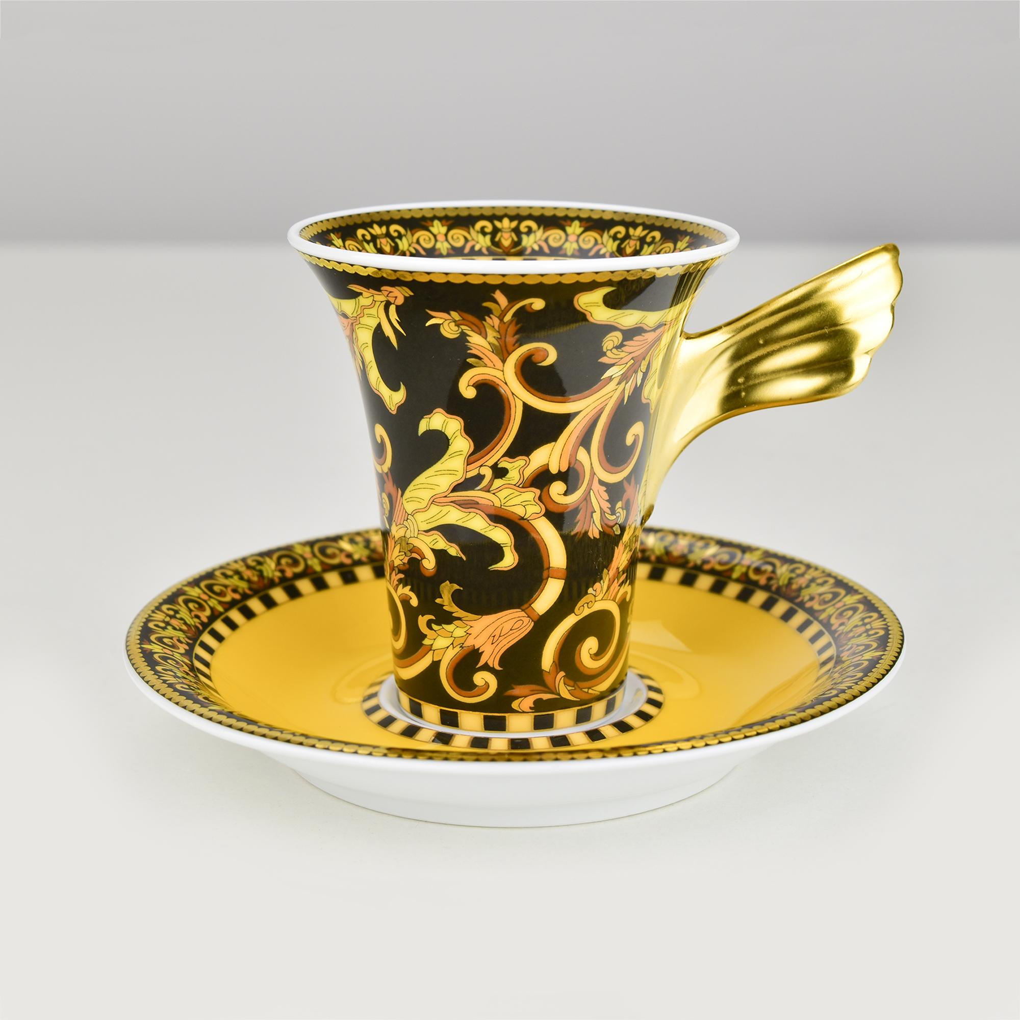 This luxurious Rosenthal Versace espresso/mocha cup and saucer collection is an exceptional example of artistic porcelain design. The shape of the cup was designed by Paul Wunderlich. The striking flared cup features a bold black and gold 