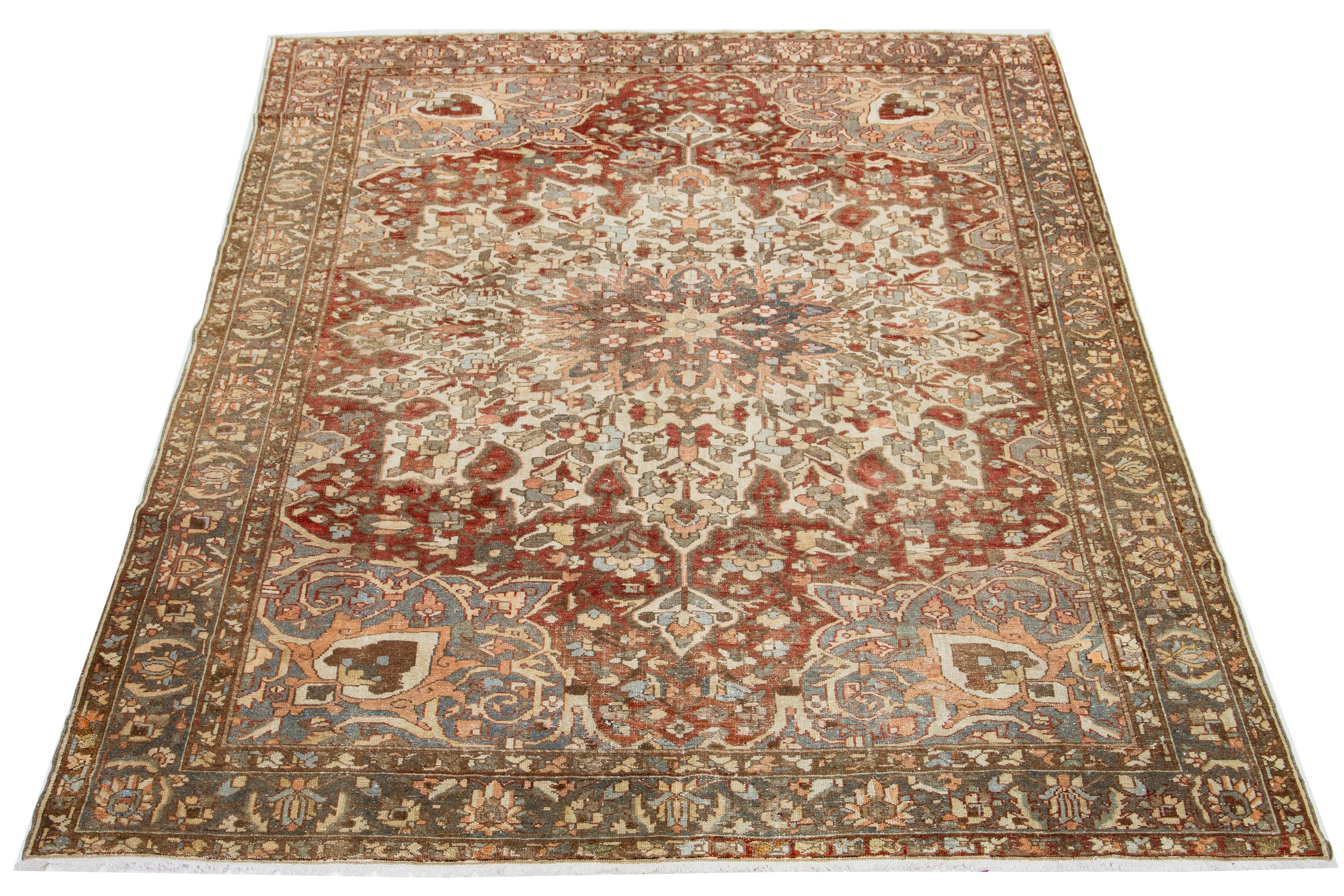 This is a beautiful Antique Bakhtiari hand-knotted wool rug with a rust-colored field. The Persian rug showcases a timeless rosette motif with peach, beige, and blue hues.

This rug measures 9'1