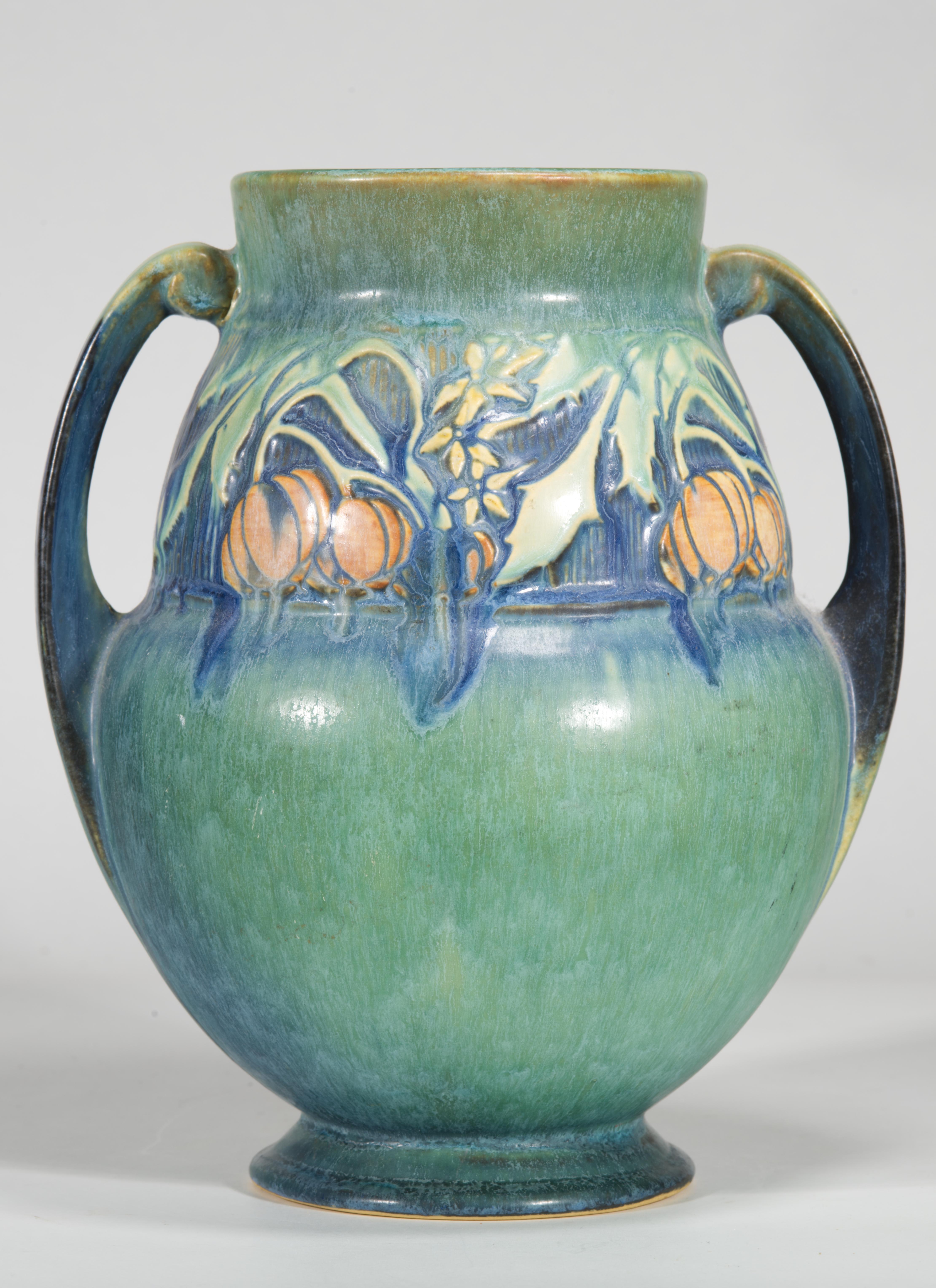 Il vaso vintage della linea Baneda presenta due manici ad anello, un'ampia fascia di decori nella parte superiore del vaso e un bellissimo smalto verde con accenti di smalto blu. Questo è il modello 596 del catalogo di Roseville. Questo modello in