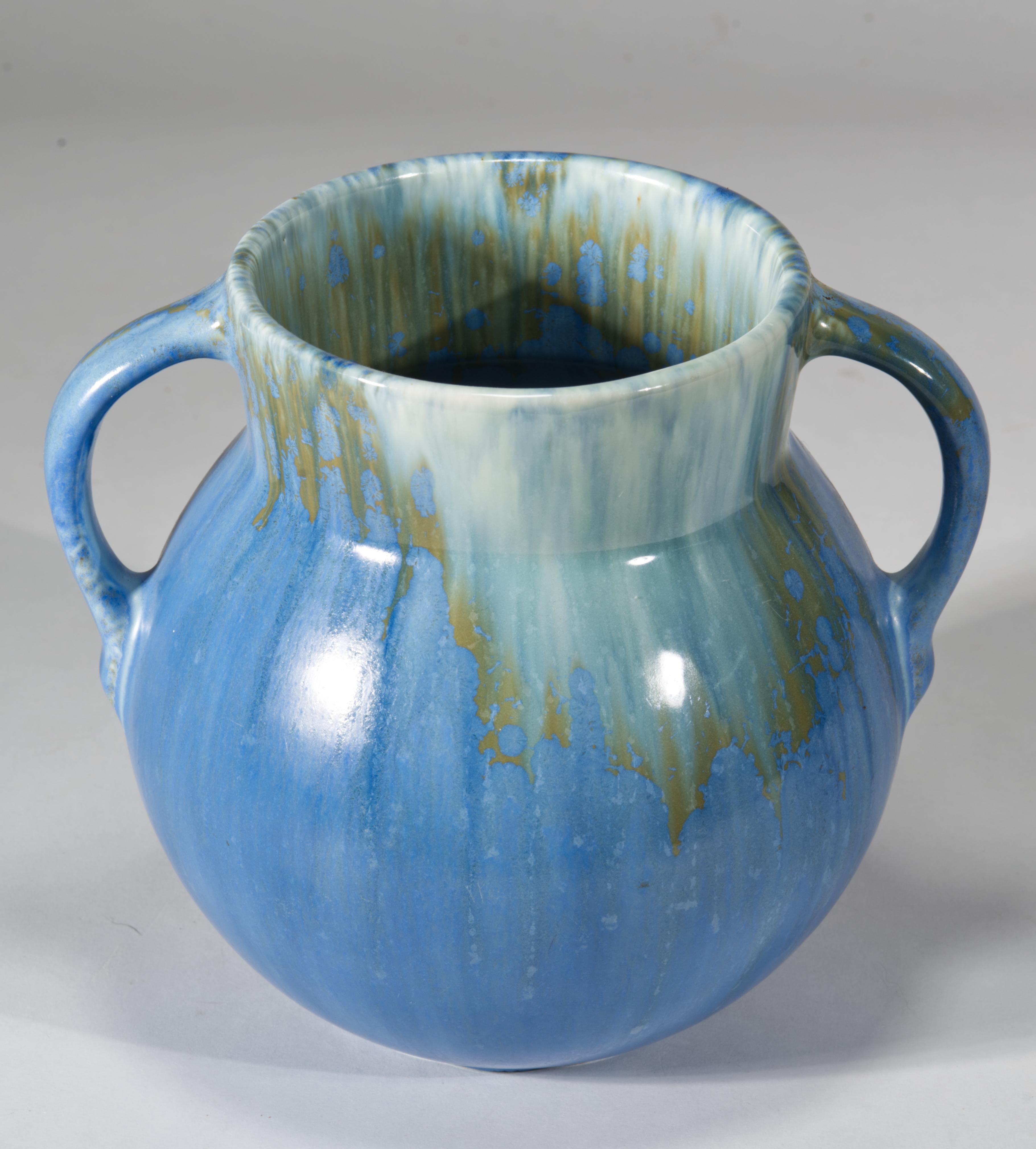 Le vase vintage présente une glaçure mate bleue mélangée avec un effet de glaçure semi-brillante jaune crème autour du bord sur les surfaces intérieures et extérieures et sur les poignées. Le vase a une forme Art déco avec deux anses ; la forme