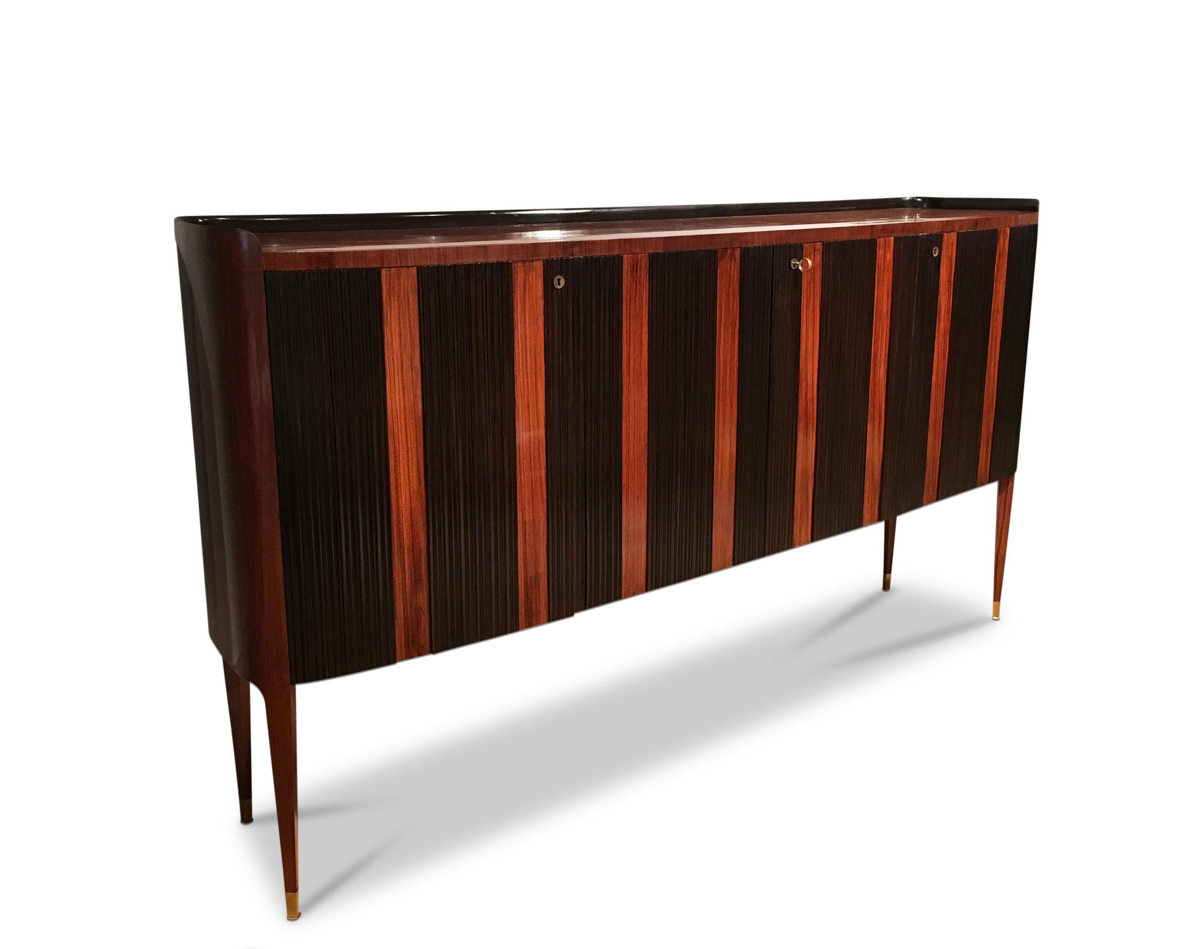 The two-tone fluted design with a gallery top supported on tapered legs with brass sabots having a fitted interior.
 