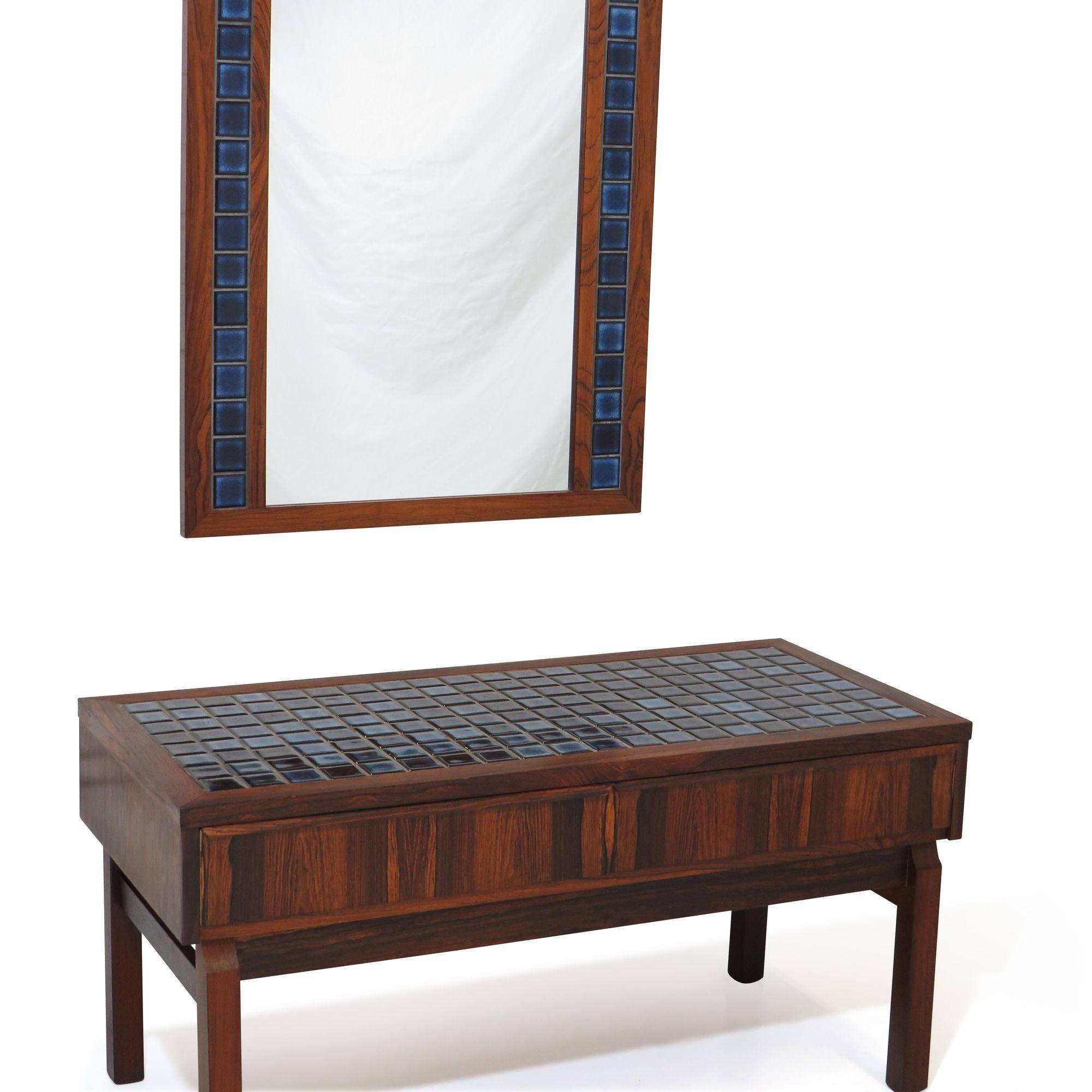 Danish entry cabinet and mirror crafted of rosewood with blue tile inlay, two small drawers for storage, raised on squared rosewood legs. Excellent condition with minor signs of age and use.
 
Cabinet measurements 
W 35.38'' x D 16.25'' x H