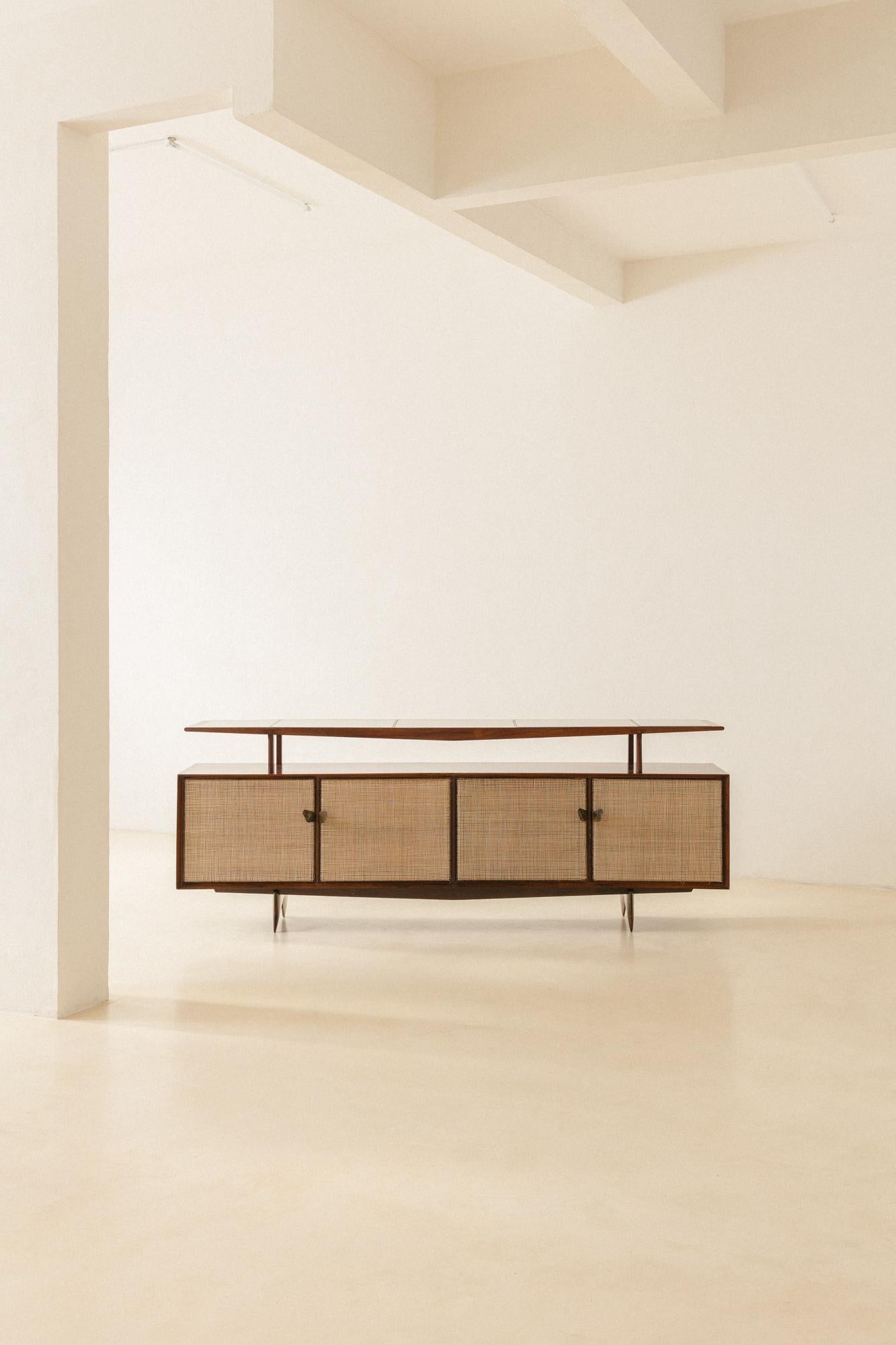 Martin Eisler (1913-1977) designed this exceptional credenza in the 1950s. Made of stunning rosewood with doors covered in natural cane, there are so many unique details that it is hard to choose what to highlight: the graceful diagonals present in