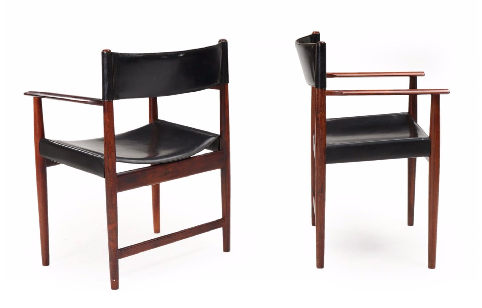 A pair of rosewood armchairs upholstered in seat and back with black full-grain leather.
Model 414. Designed 1961.
Manufactured and marked with metal plaque by Sibast Furniture. 

Additional images, close-ups and detailed condition report
