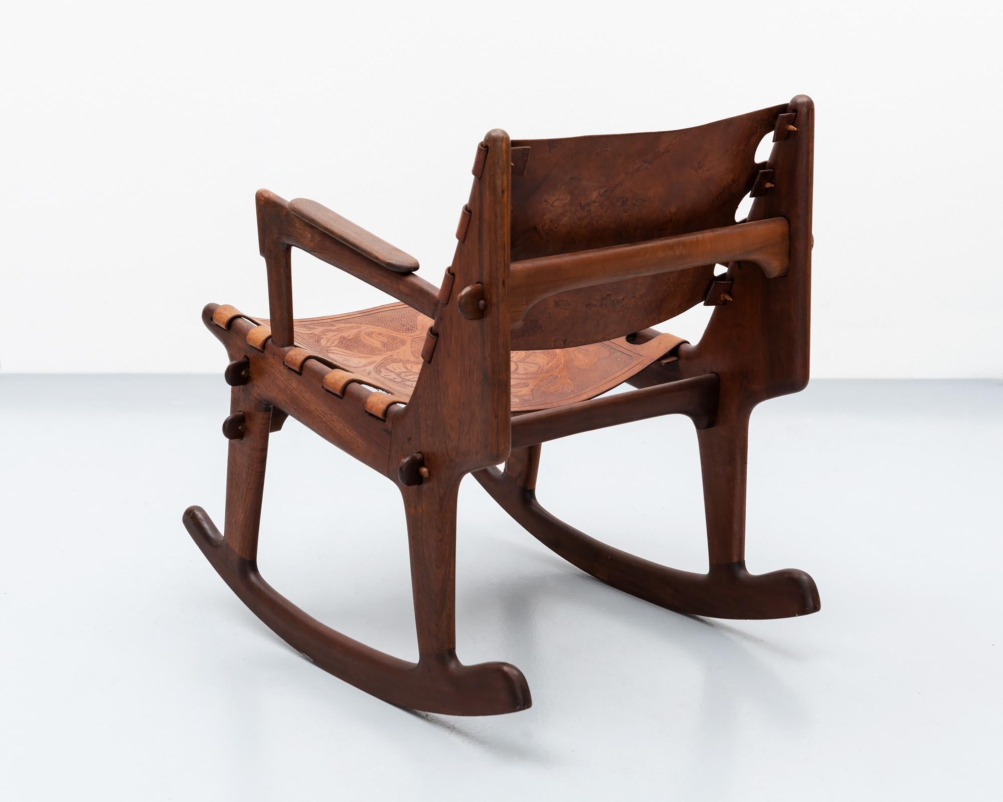 A rocking chair by South American modernist Angel Pazmino for Muebles de Estilo in solid rosewood with heavy, hand-tooled leather seat and back. Classic Pazmino peg joinery and Scandinavian Modern influences characterize this rocker. Ecuador, 1960s