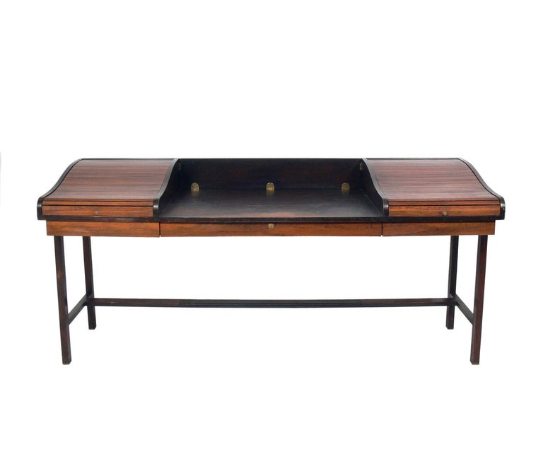 Rosewood and mahogany roll top desk, designed by Edward Wormley for Dunbar, American, circa 1960s. This piece is being refinished and will look incredible when completed. The price noted includes refinishing. 

The tambour roll up doors open to