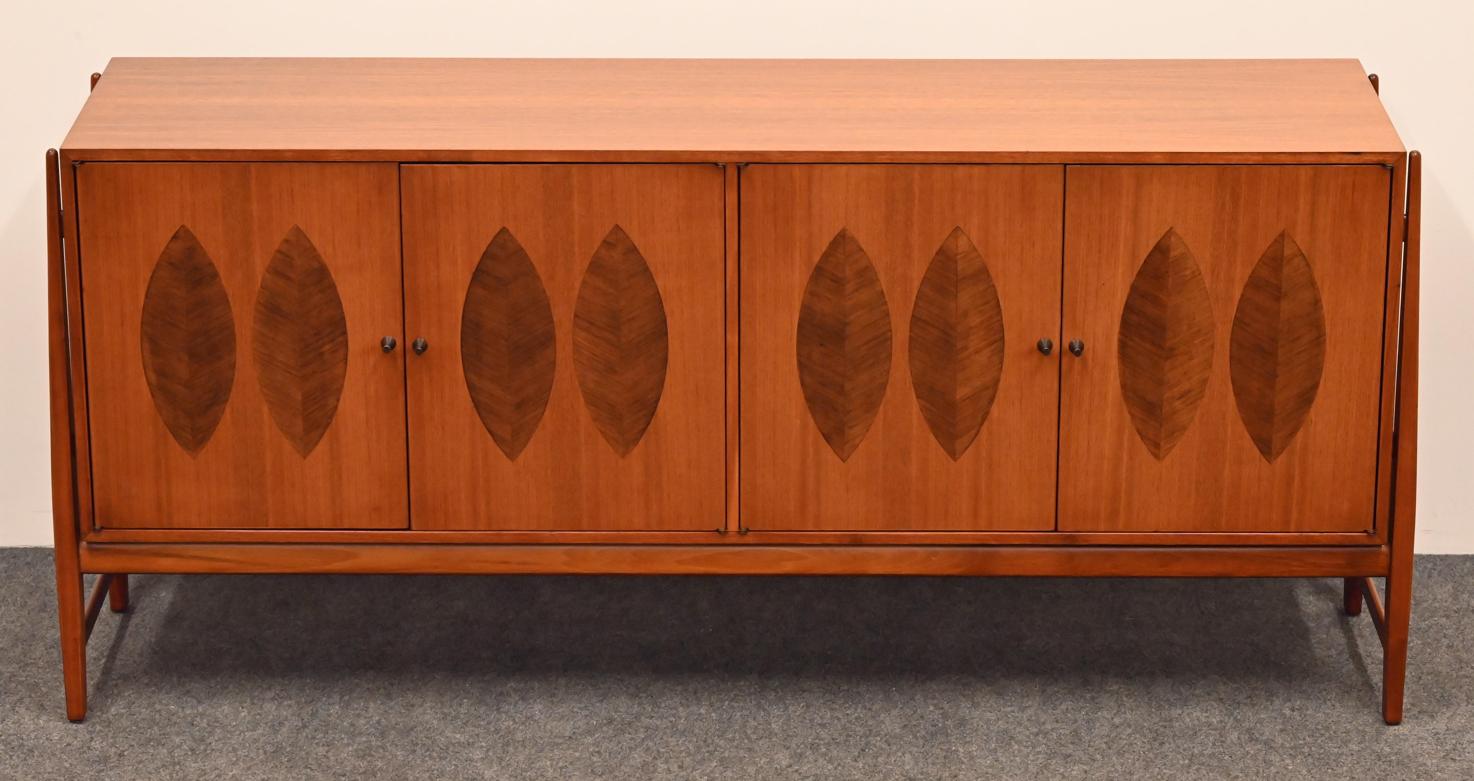 An organic modern Credenza designed by Kipp Stewart for Calvin. This beautiful cabinet has four doors, two drawers, and a new glass shelf in the interior for ample storage. The gorgeous walnut inlay of a stylized leaf design showcases this piece.