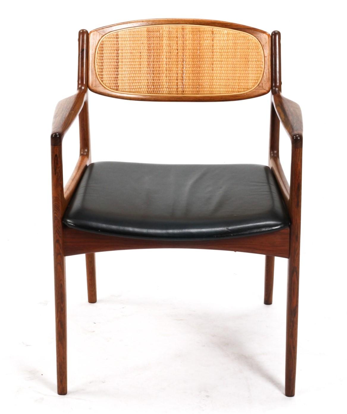 A rare Kofod Larsen armchair in solid rosewood with a very nice contrast of the caned backrest and the leather seat. This comfortable office chair was designed by the designer in the 1960s and has the essence of form and function of Scandinavian
