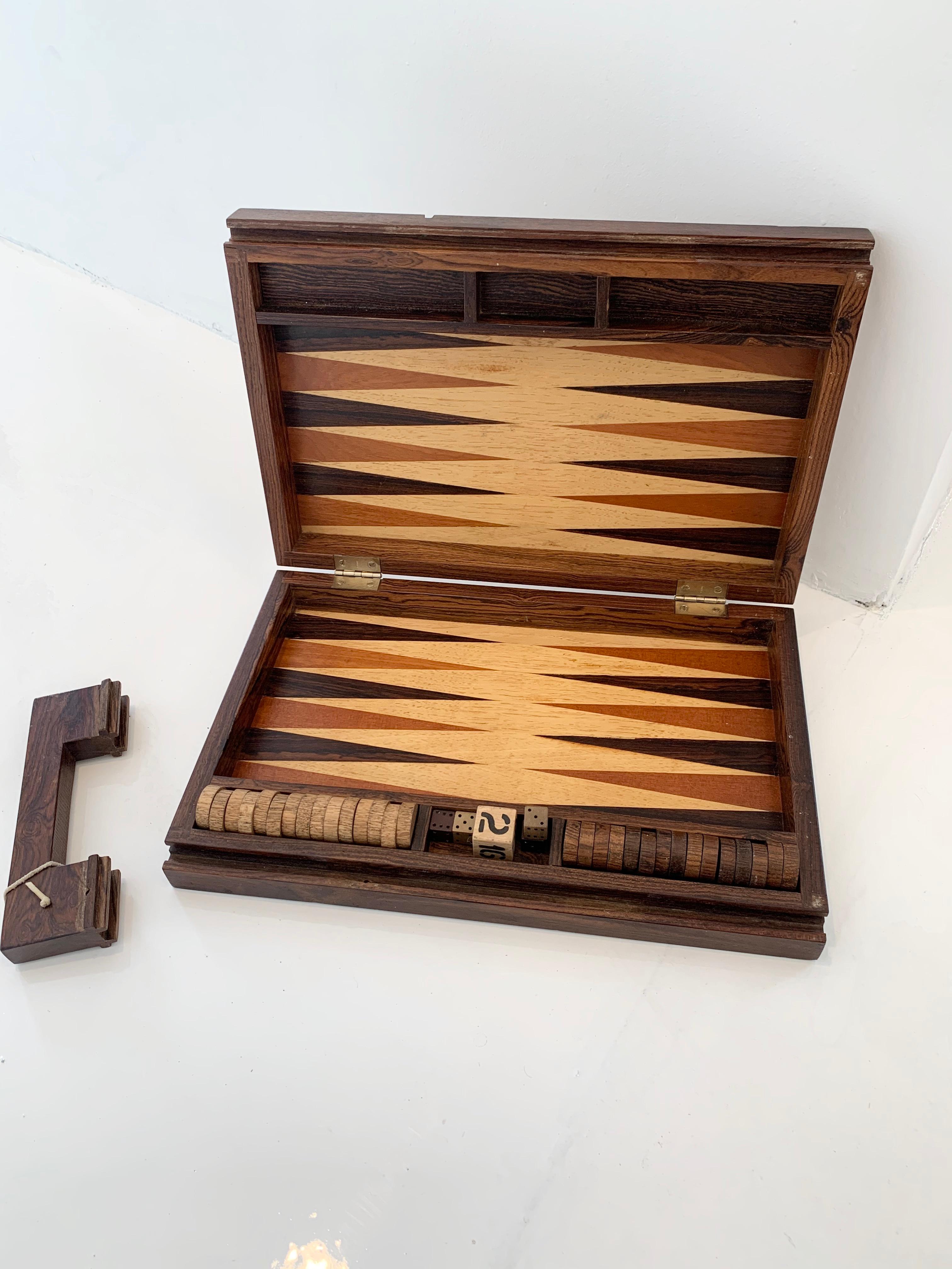 Stunning Rosewood portable backgammon board. Handle slides out to open. Inset brass pin to hold handle in place while not in use. Board includes all wooden pips, wood dice and wood doubling cube. Designed by Don Shoemaker. Gorgeous piece. Good