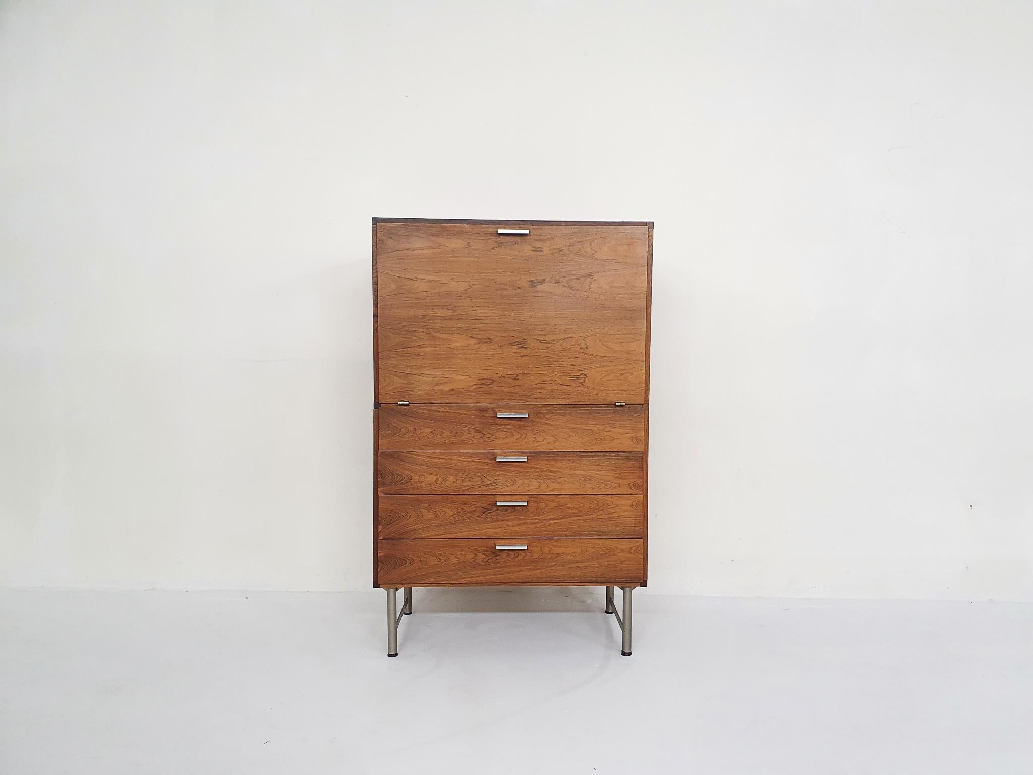 Rosewood veneer bar cabinet on metal legs. Designed in The Netherlands by Cees Braakman for Pastoe in 1959. 
Cees Braakman was a Dutch furniture designer who worked for UMS Pastoe in the midcentury. He designed many beautiful pieces with the “U+N