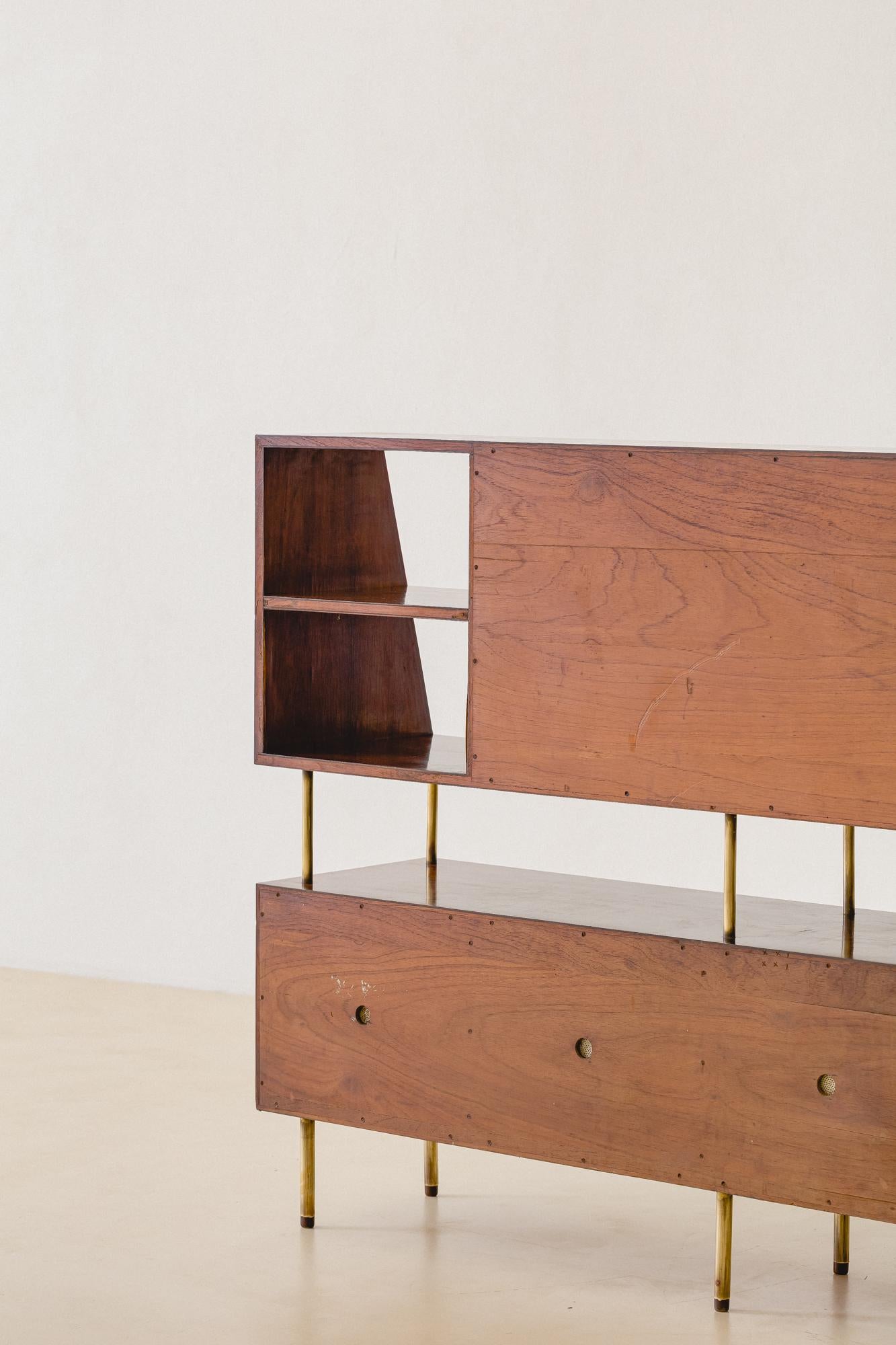 This bookshelf is a rare and elegant piece designed by Martin Eisler and produced by Forma S.A. Móveis e Objetos de Arte in 1955. It presents a structure in Rosewood, with brass feet and supports.

The piece presents several storage compartments,