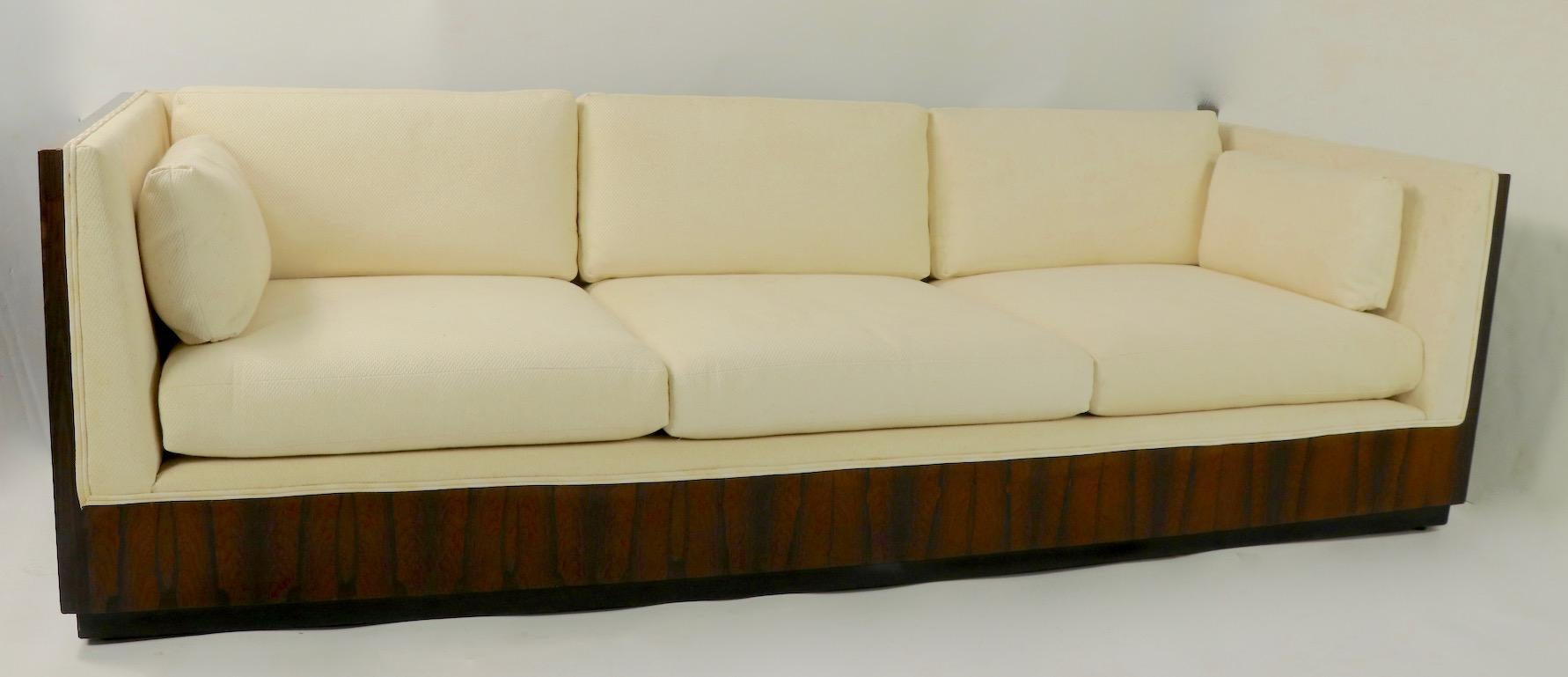 Chic architectural case, or box, sofa designed by Milo Baughman for Thayer Coggin. Nice large full size example having vibrant rosewood veneer case and original off white fabric. This example is selling in original, untouched condition, it shows