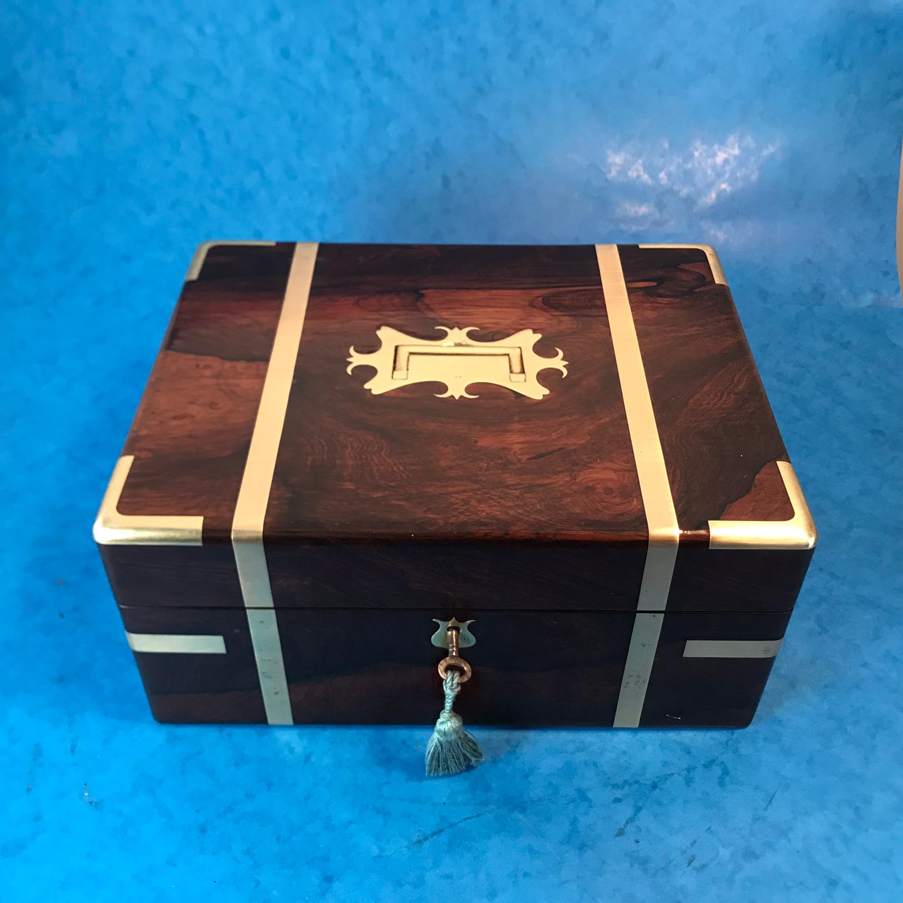 Rosewood brassbound jewelry box, the jewelry box dates back to 1830, its brassbound in a contemporary style with military flush handles to the sides with a wonderful shaped handle to the top. It has a side drawer with a pin that holds the drawer in