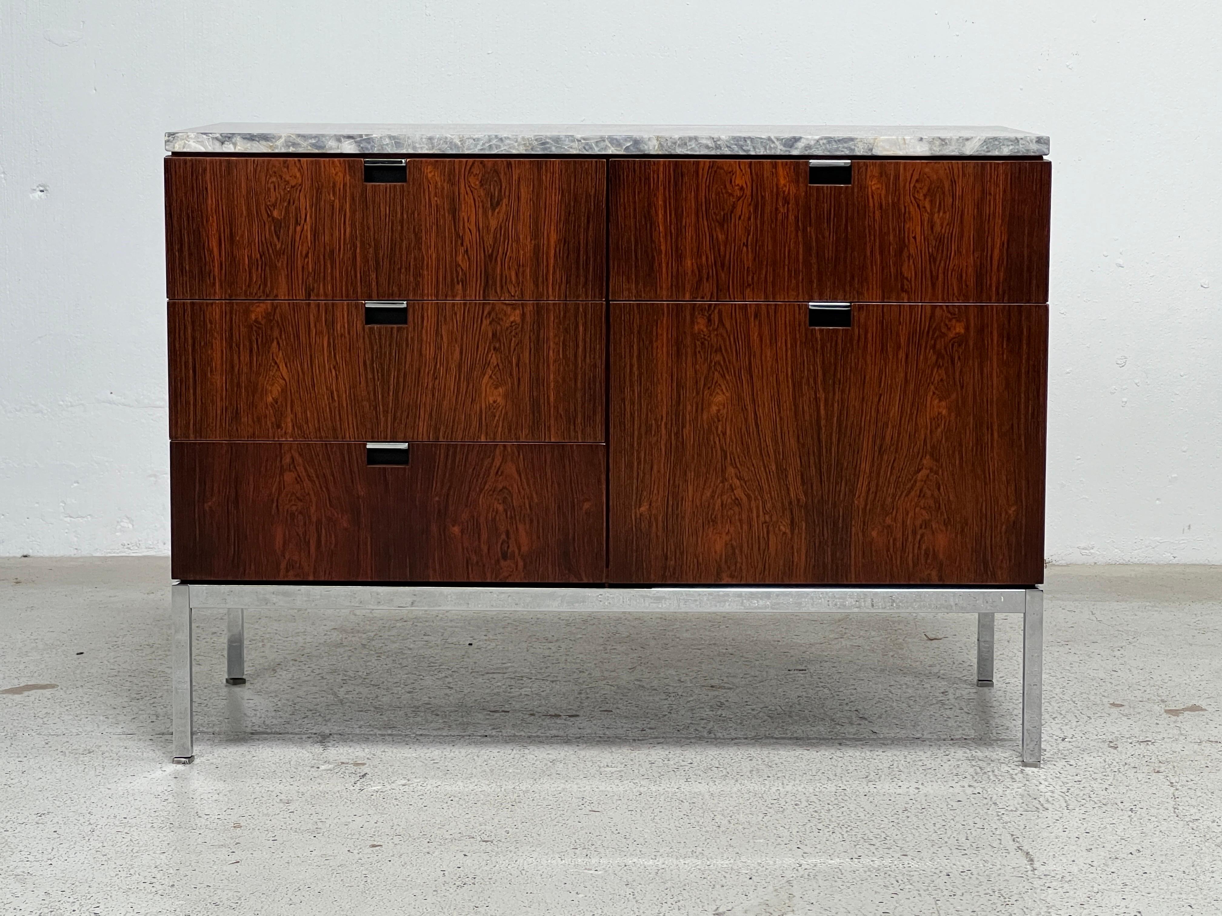 A rosewood credenza with finished back and marble top. Designed by Florence Knoll for Knoll.