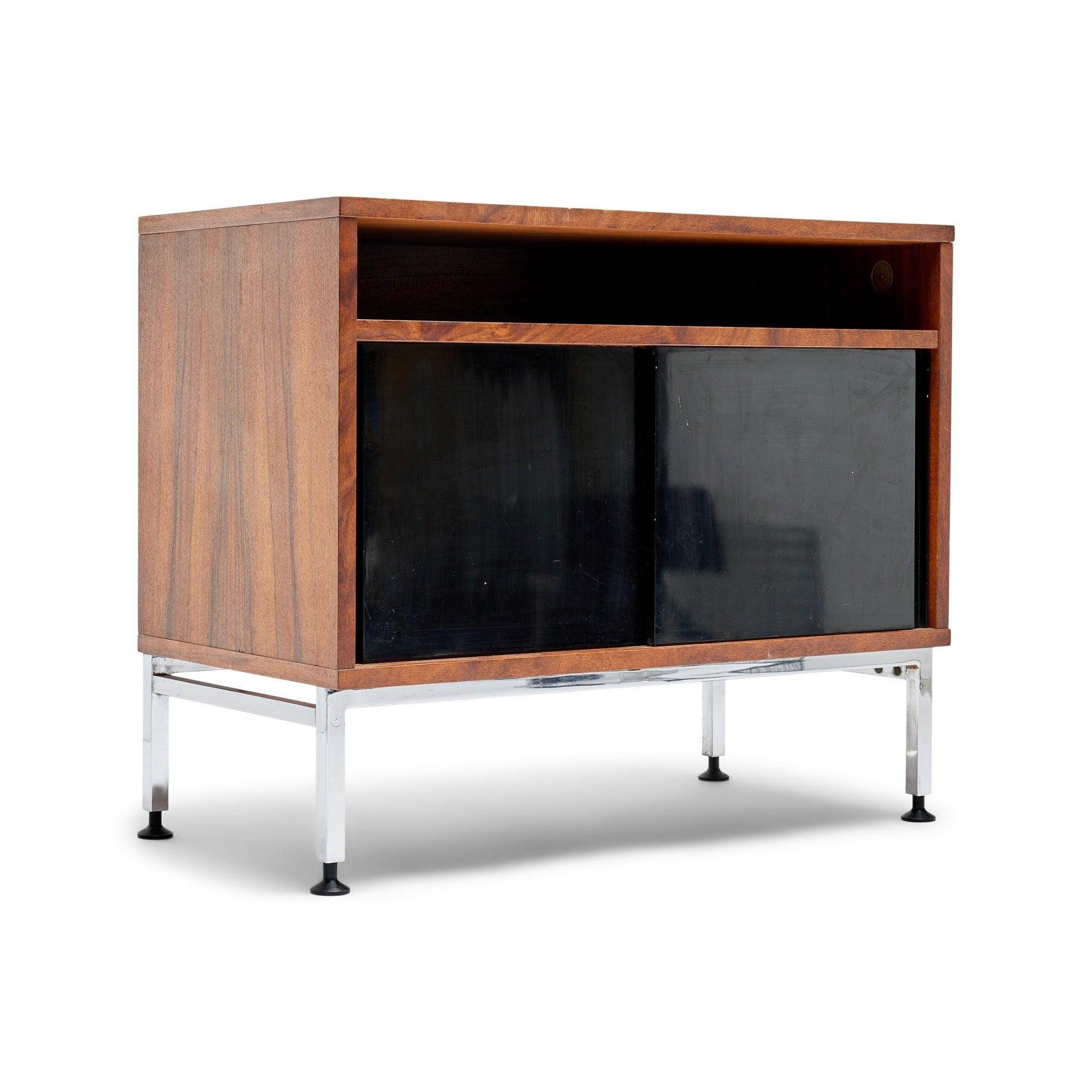 Une armoire en bois de rose avec des portes coulissantes noires et une étagère reposant sur un cadre à quatre pieds en acier chromé avec des pieds réglables. Signé.