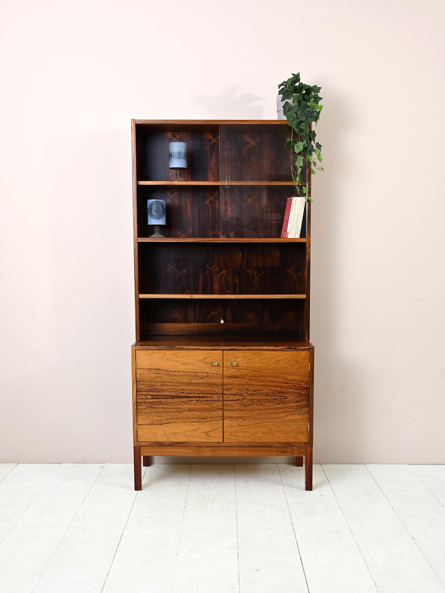 1960s modern antique bookcase sideboard.
 
Consists of a cabinet with hinged doors on which the shelving system rests. At the top, the shelves are closed by a display cabinet.
The precious rosewood and refined finish make it a piece of timeless