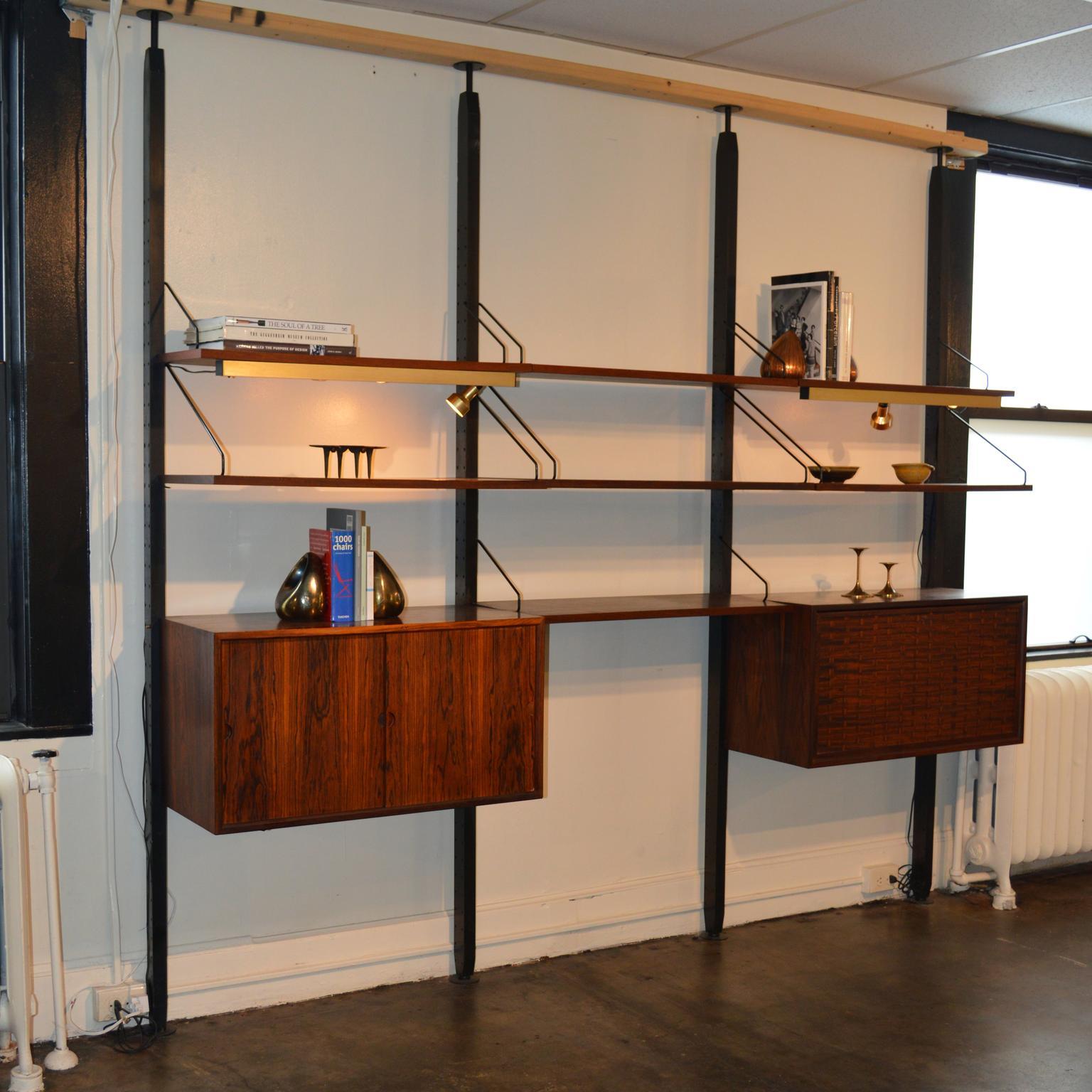 Wall unit designed by Poul Cadovius in 3 bays, 8 shelves, 2 cabinets. This system is both rare and stunning, made from Brazilian rosewood. A seldom-seen tension pole system creates pressure on the floor and ceiling with spring-loaded feet in the