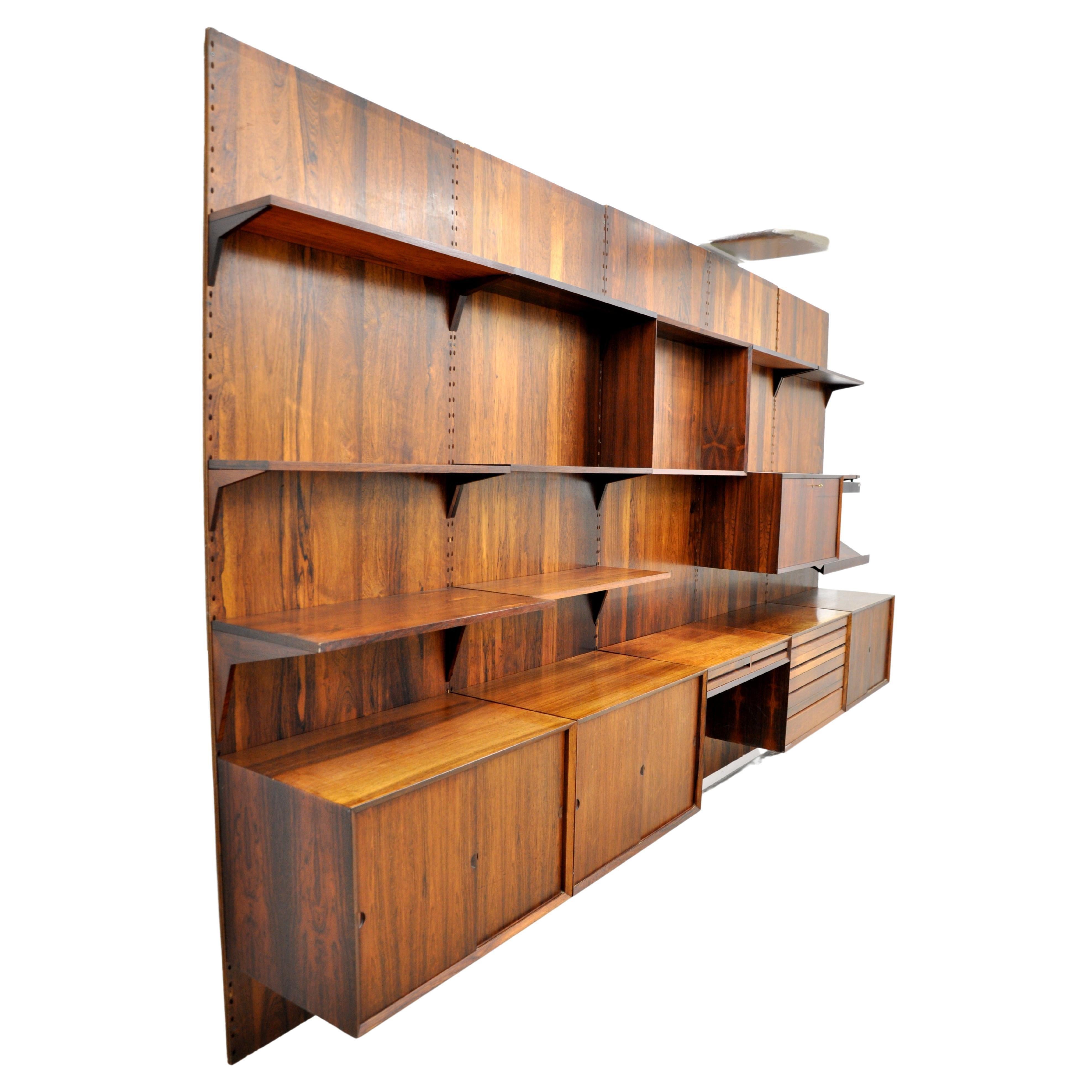 Midcentury Danish Modern five bay Brazilian rosewood modular wall shelving unit, designed by Poul Cadovius, manufactured by Royal System, Inc. 

The spectacular vintage wall system features components that can be interchanged and placed according to