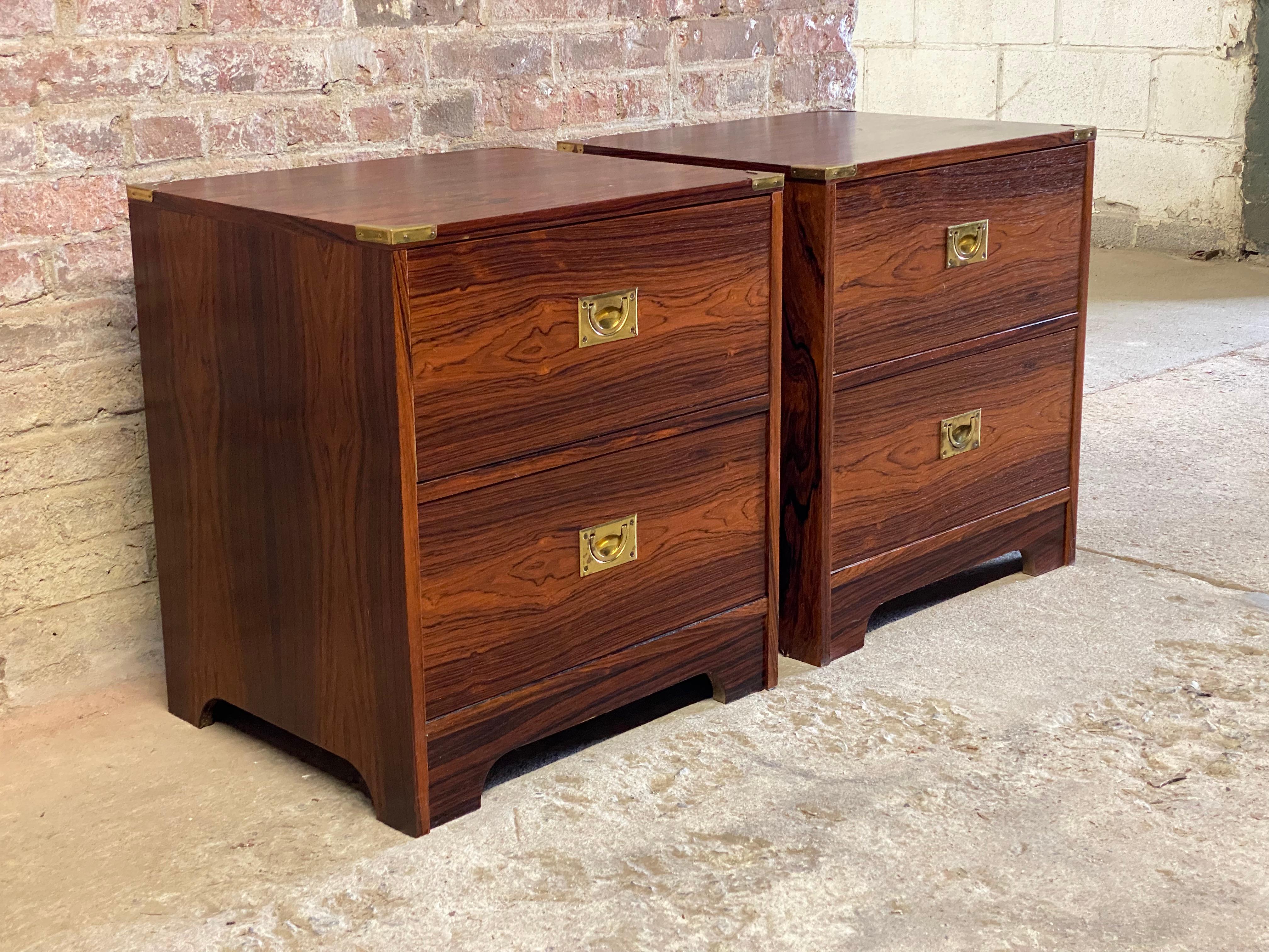 A wonderful pair of highly figured Rosewood Campaign style two drawer end tables or night stands. Brass corner accents with recessed brass hardware pulls. Each has two deep drawers with arched bases. Circa 1970. Good overall condition and