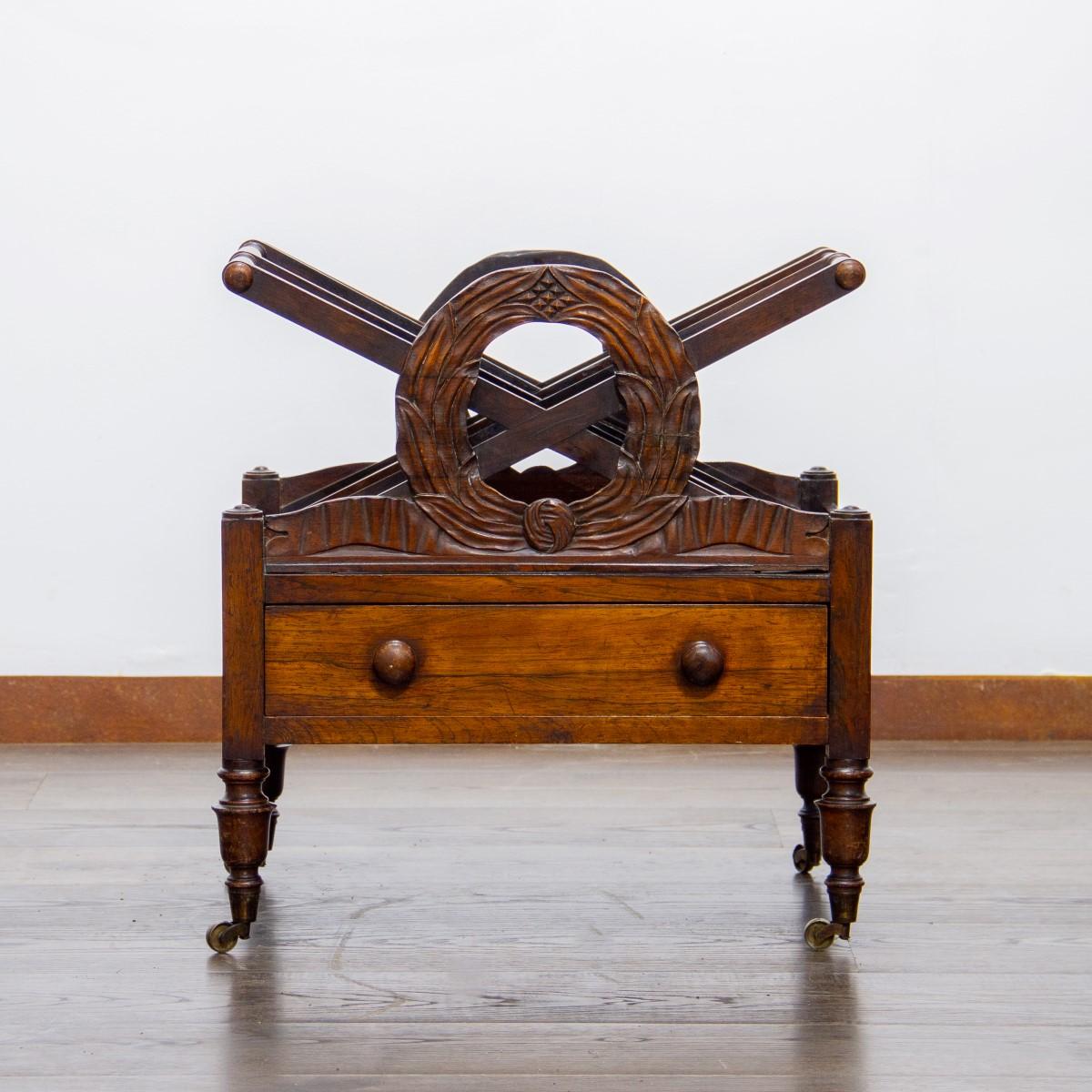 Un William IV Canterbury realizzato in William Rosewood con corone di foglie di alloro che fiancheggiano i divisori con cornice a 'X', sotto c'è un piccolo cassetto con due maniglie tornite, il tutto su quattro gambe tornite con rotelle in