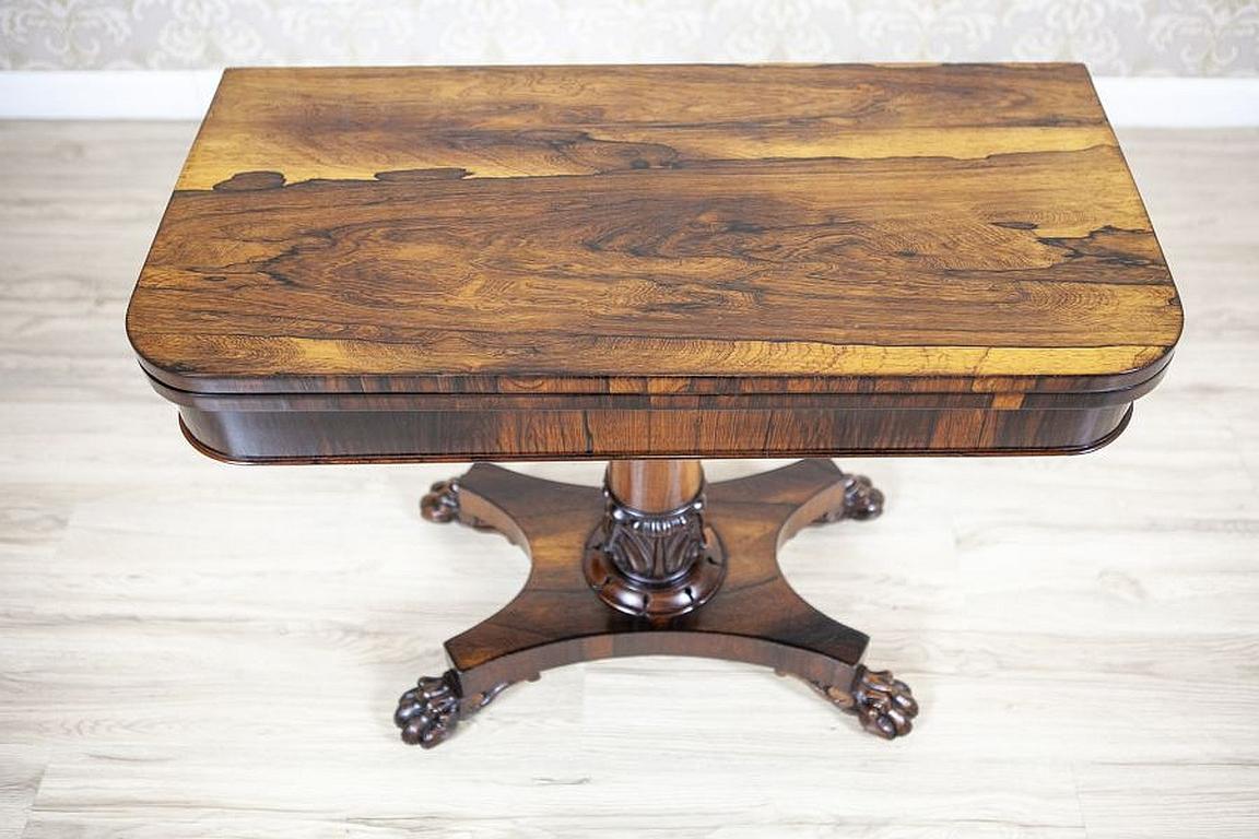 Fold-out Rosewood Card Table from the Turn of the 19th and 20th Centuries

We present this rectangular foldout card table. The whole piece is supported on a pedestal on a square base, which is finished with claws. After folding out, the top is lined