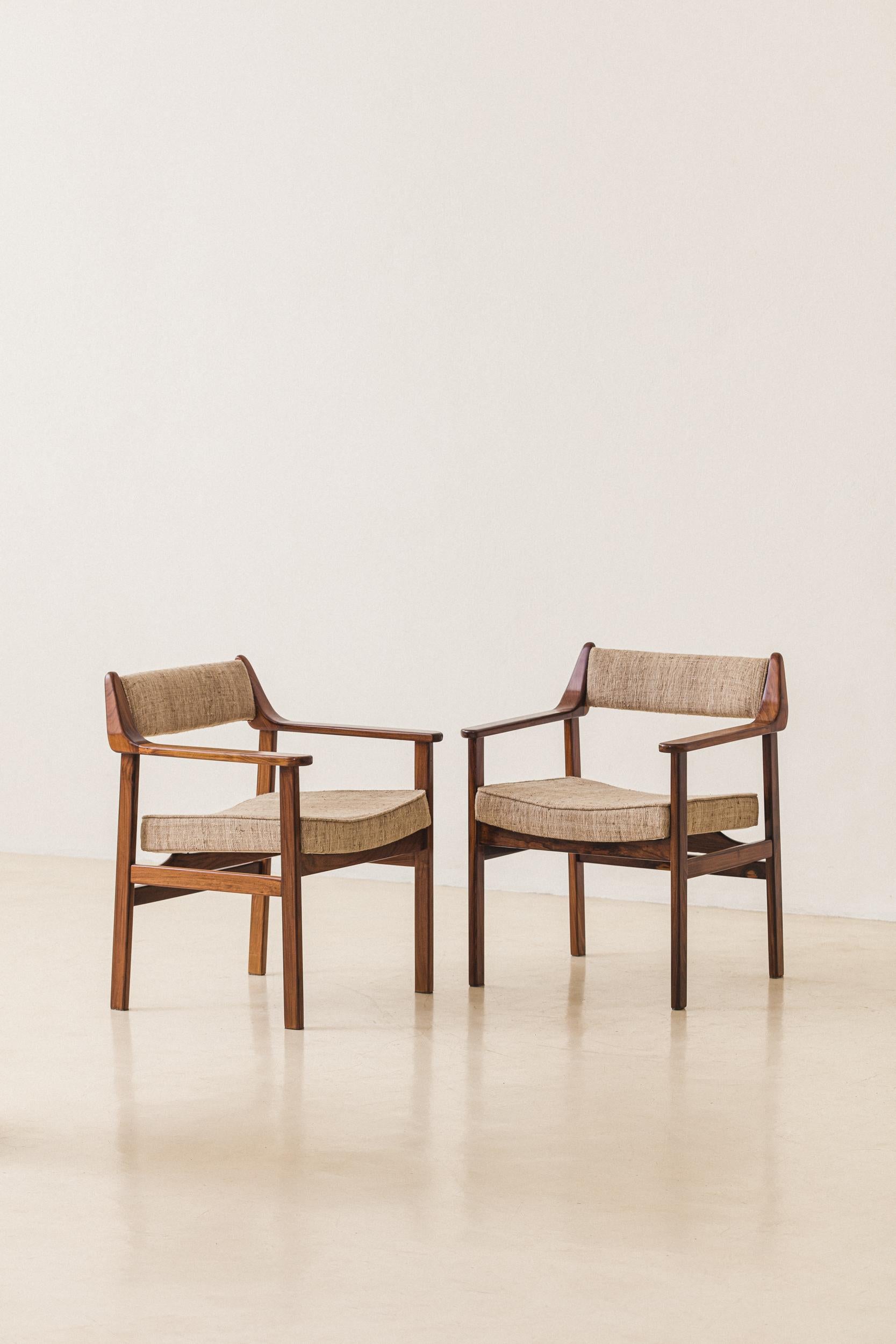 This pair of chairs with armrests made in solid rosewood and fabric was produced by Cantù Móveis e Interiores Ltda. in the 1960s. This model was manufactured with seats in cane or leather, and it was part of a collection focused, at the same time,