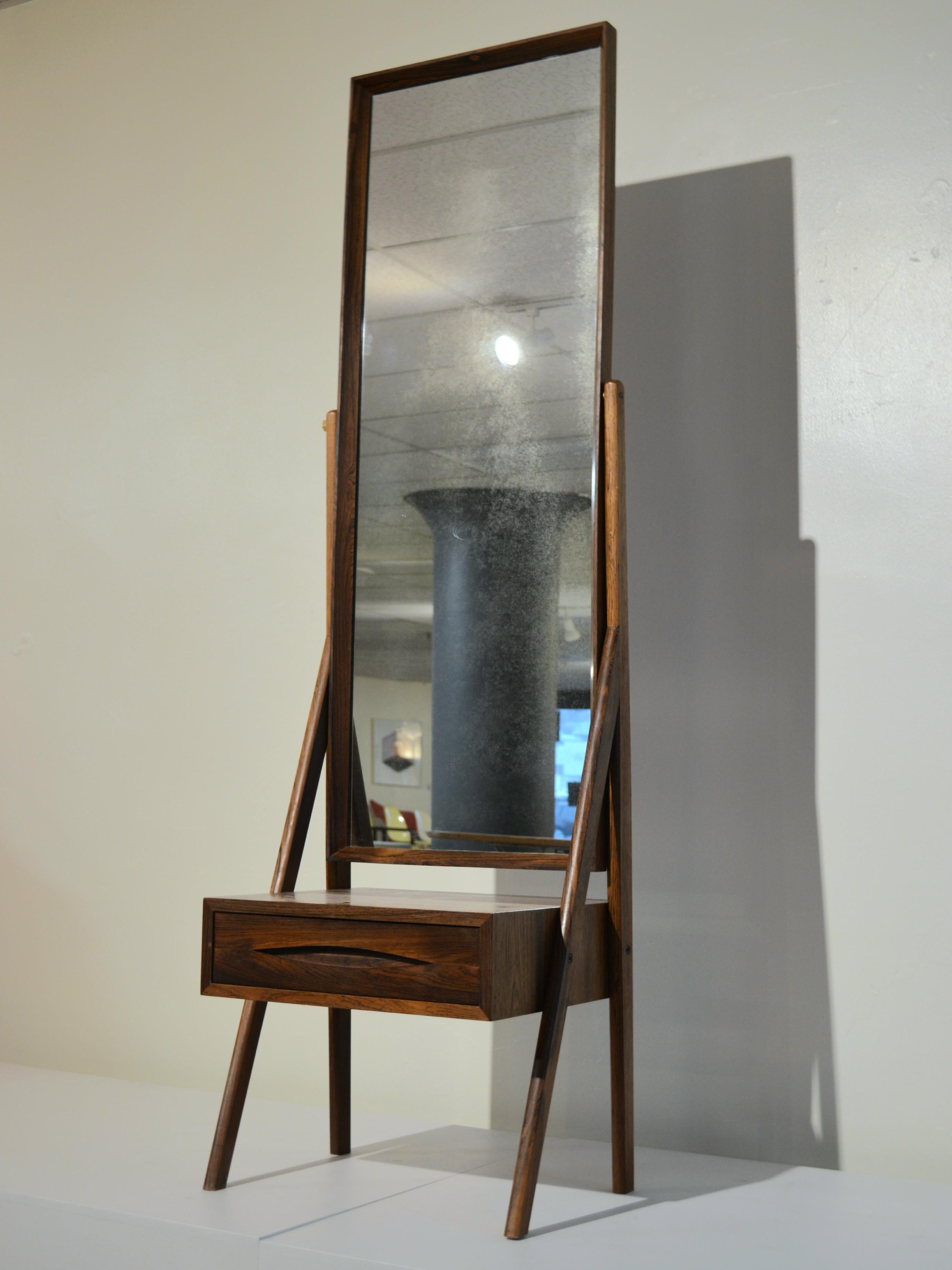 Freestanding rosewood Cheval floor mirror designed by Arne Vodder of Denmark, circa 1960s. The adjustable wood-framed mirror appears to float on it's asymmetrical solid Brazilian rosewood base. The piece can serve brilliantly as a valet, as it has a