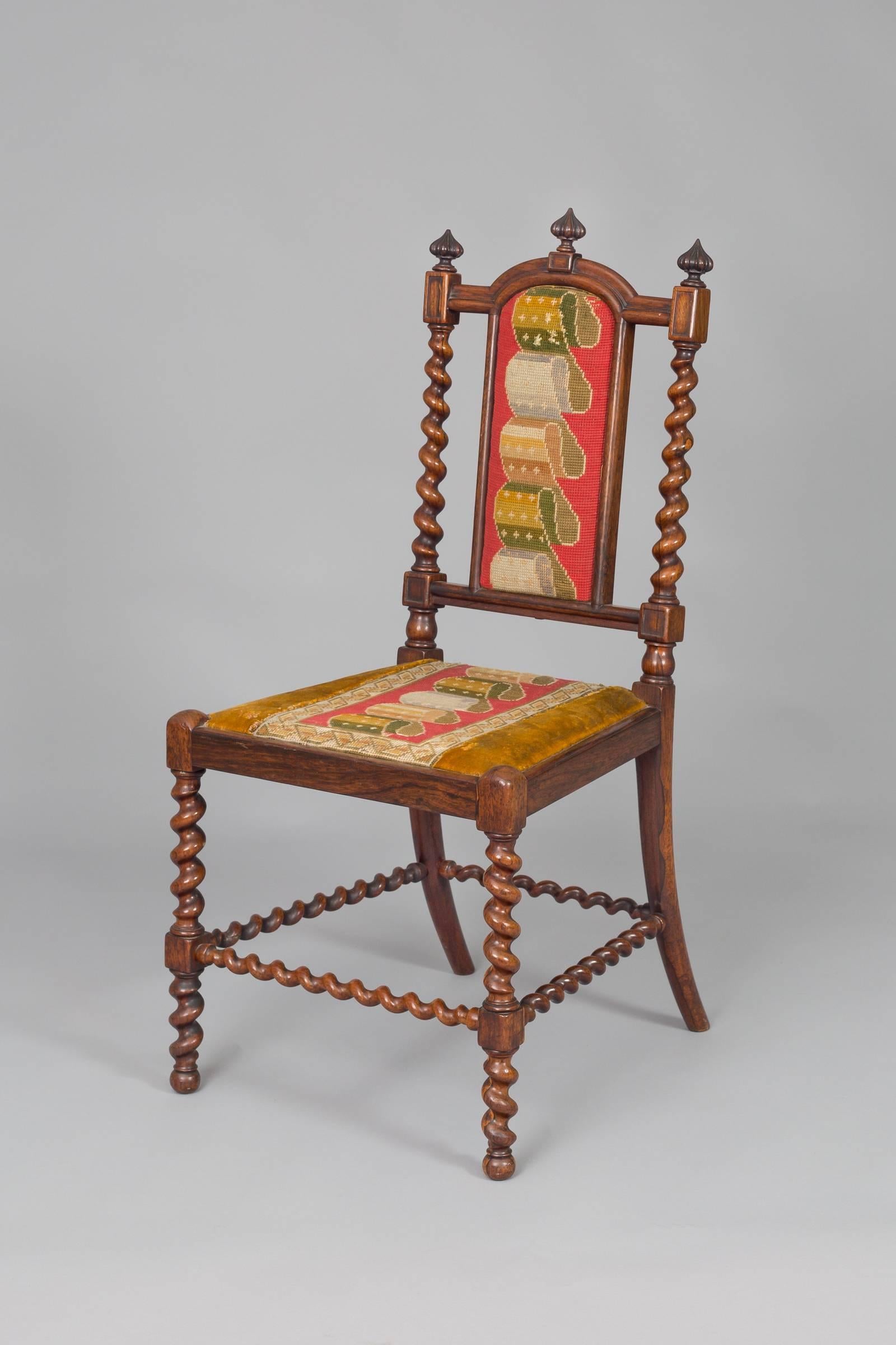 Early Victorian rosewood child’s side chair with barley twist uprights, legs and stretchers, three carved finials on the shaped top rail, colorful needlework back and seat done in a ribbon pattern, splay back legs.