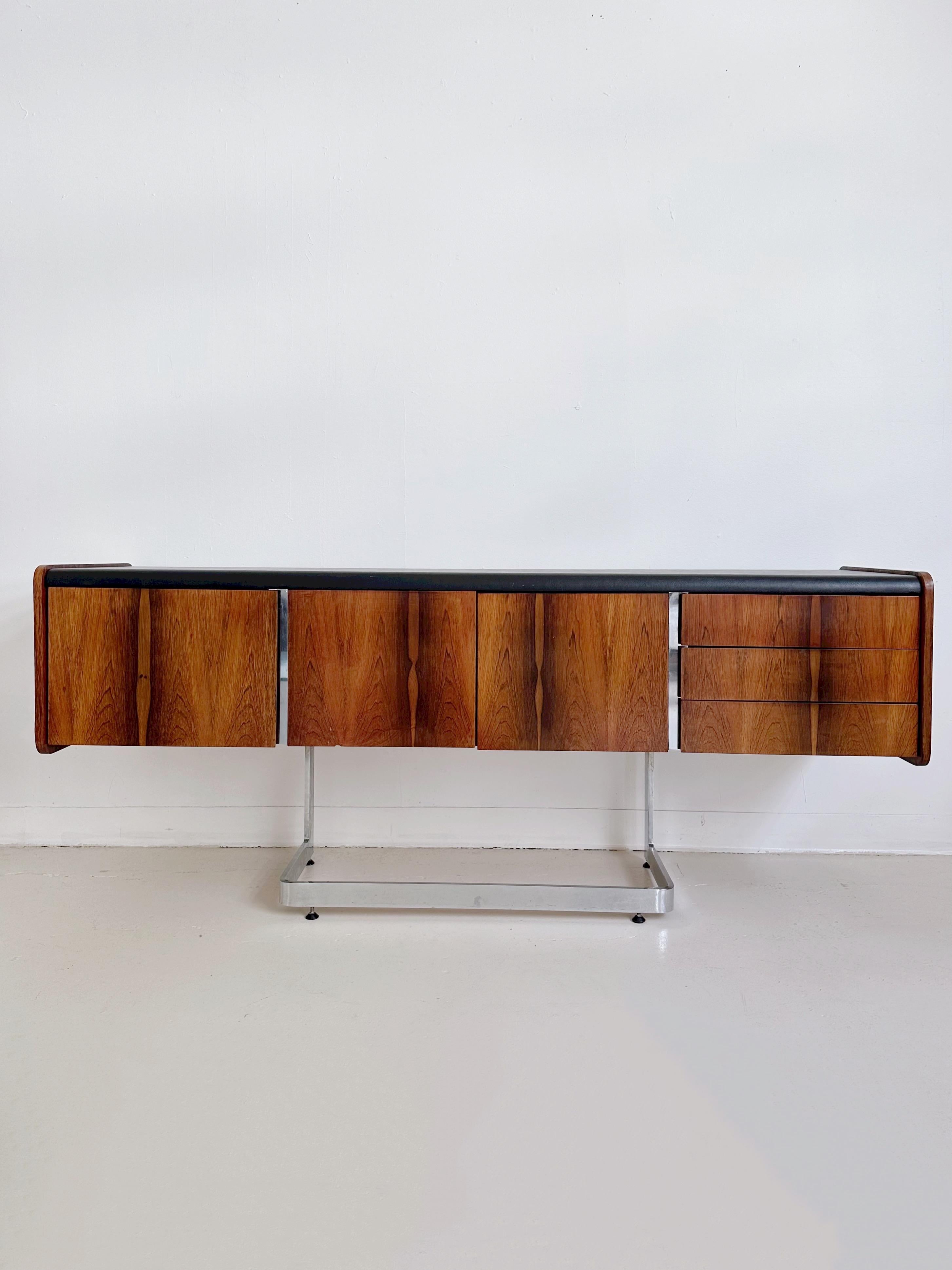 Rosewood Credenza with Cantilevered Chrome Base and Black Leatherette Top by Ste Marie & Laurent, 70s

Features a deep file drawer, three pullout drawers and a centre storage cabinet.


*Excellent condition, only minor signs of use.