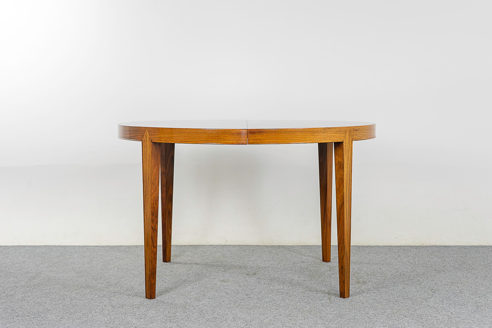Rosewood Danish dining table by Haslev, circa 1960's. Expandable circular design, the perfect table for modern compact living spaces. Use one leaf or more depending on your needs. Metal leg swings down for extra support when second leaf is in use.