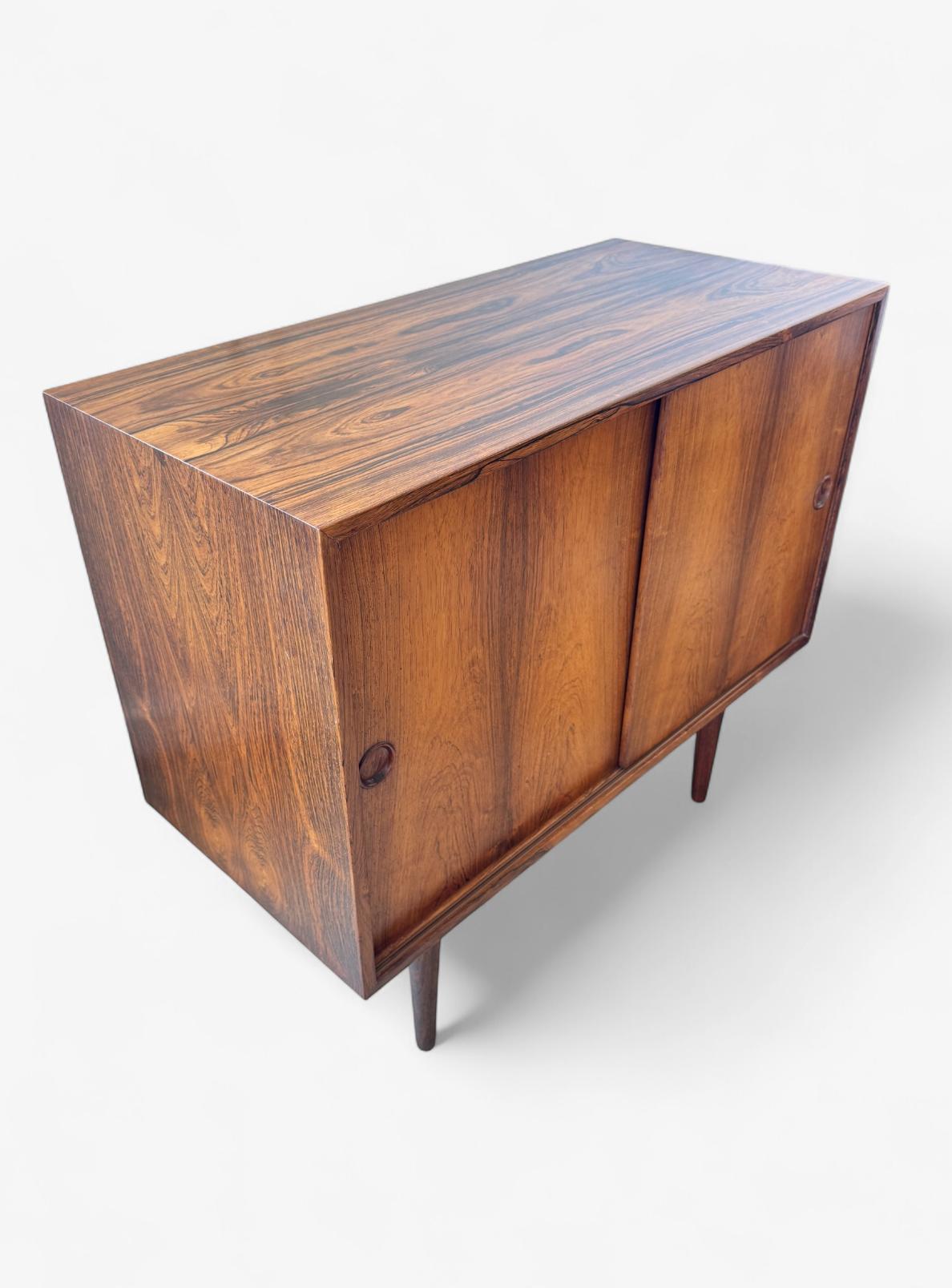 A 1960s Rosewood Cocktail Cabinet by Kai Kristiansen with solid tapering Rosewood short legs. This mid-century modern piece features impressive rosewood book-matched grain and clean lines. Ideal for collectors and interior lovers, it's a hallmark of