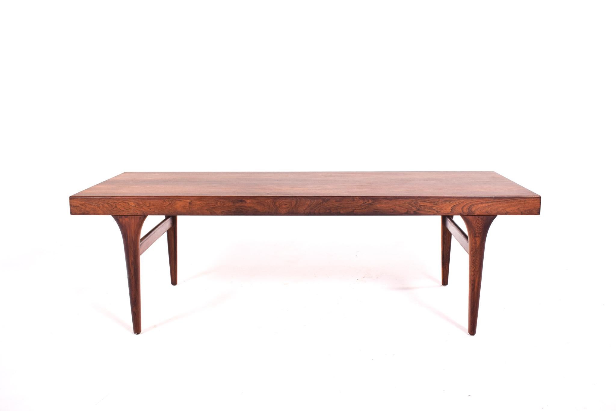 This authentic Mid-Century Modern coffee table, designed by Johannes Andersen for CFC Silkeborg, is a statement piece of the era, embodying the sleek lines and organic forms that are quintessential to Danish design. Crafted from rosewood, the table
