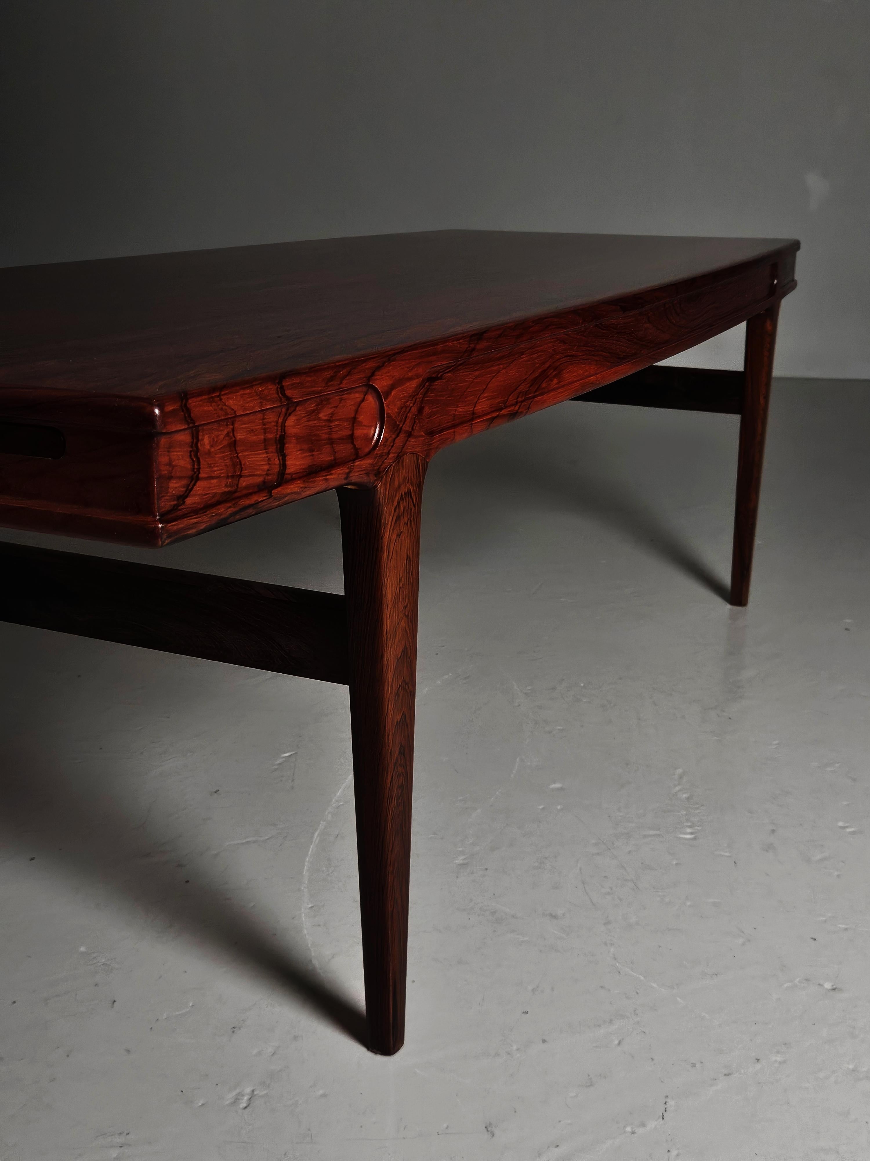 Luxueuse table basse conçue par Johannes Andersen et produite par CFC Silkeborg au Danemark dans les années 1960.

Fabriqué en bois de rose. Extensible avec deux plateaux noirs de chaque côté. 32 cm chacun. 