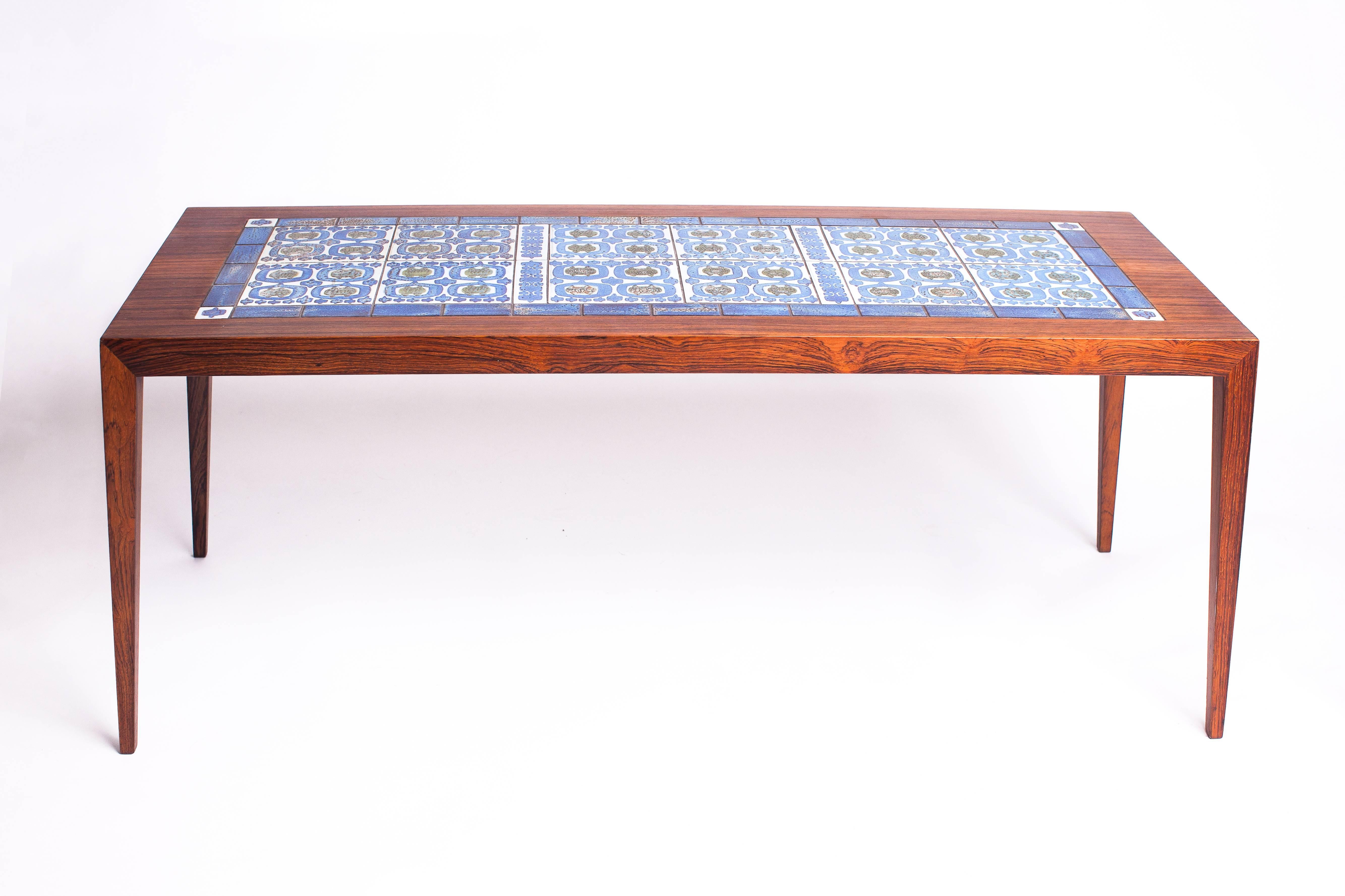 A beautifully crafted rosewood coffee table by Severin Hansen, inlaid with variegated olive green and sea blue glazed ceramic tiles in geometric patterns on a bone white field, by Royal Copenhagen.

Manufacturer’s mark and Danish control on