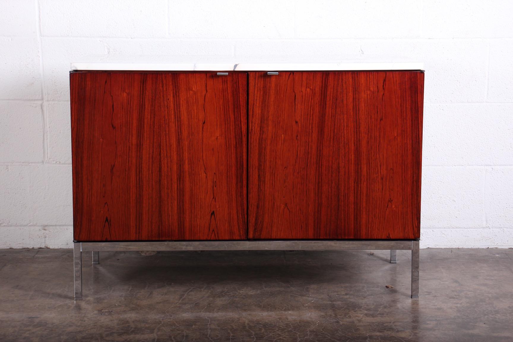 A rosewood credenza with chrome base and marble top. Designed by Florence Knoll for Knoll.
