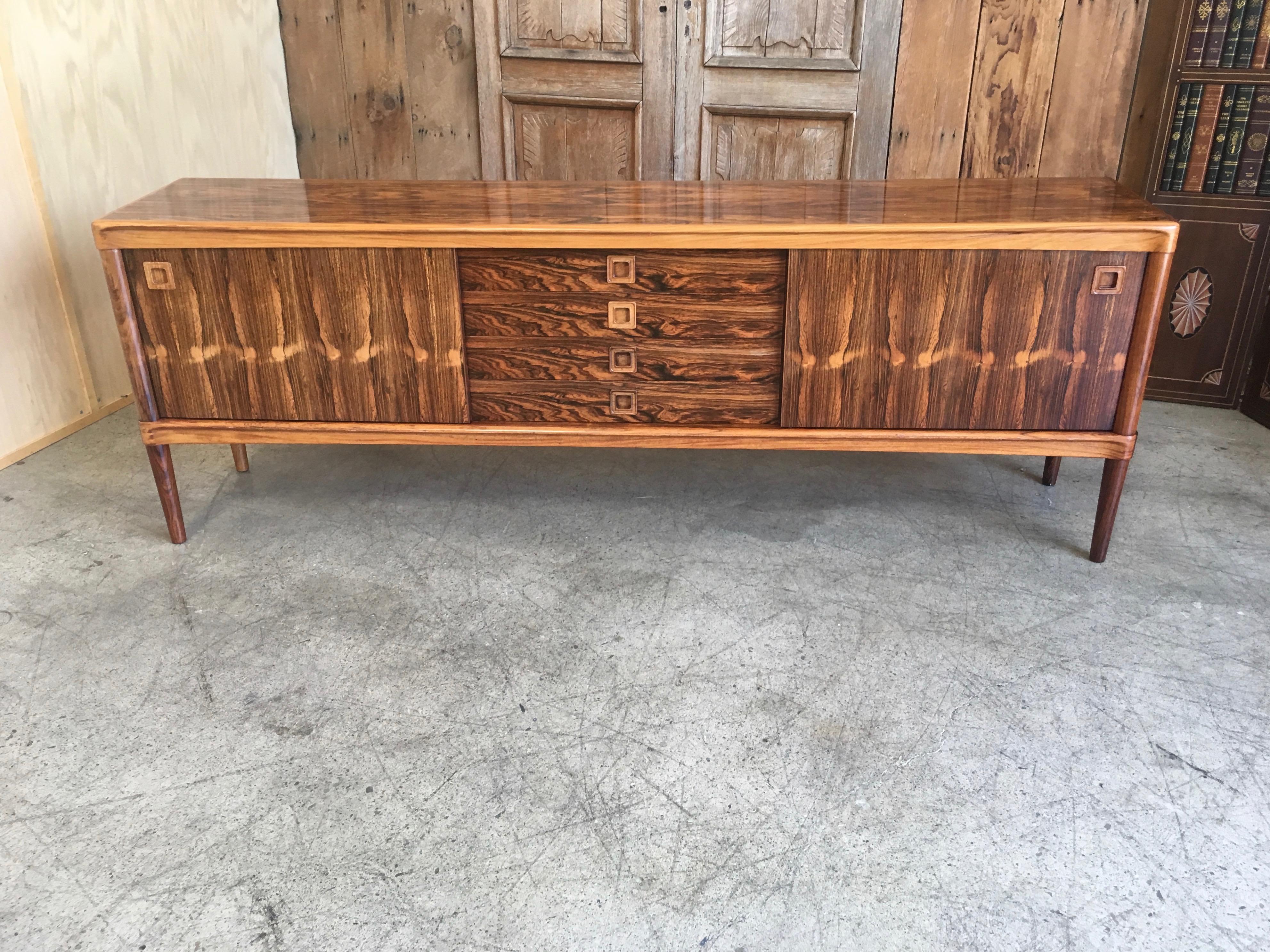 Very long rosewood Danish modern sideboard in original finish designed by H.W. Klein in Denmark with sliding doors flanking a centre drawer section.