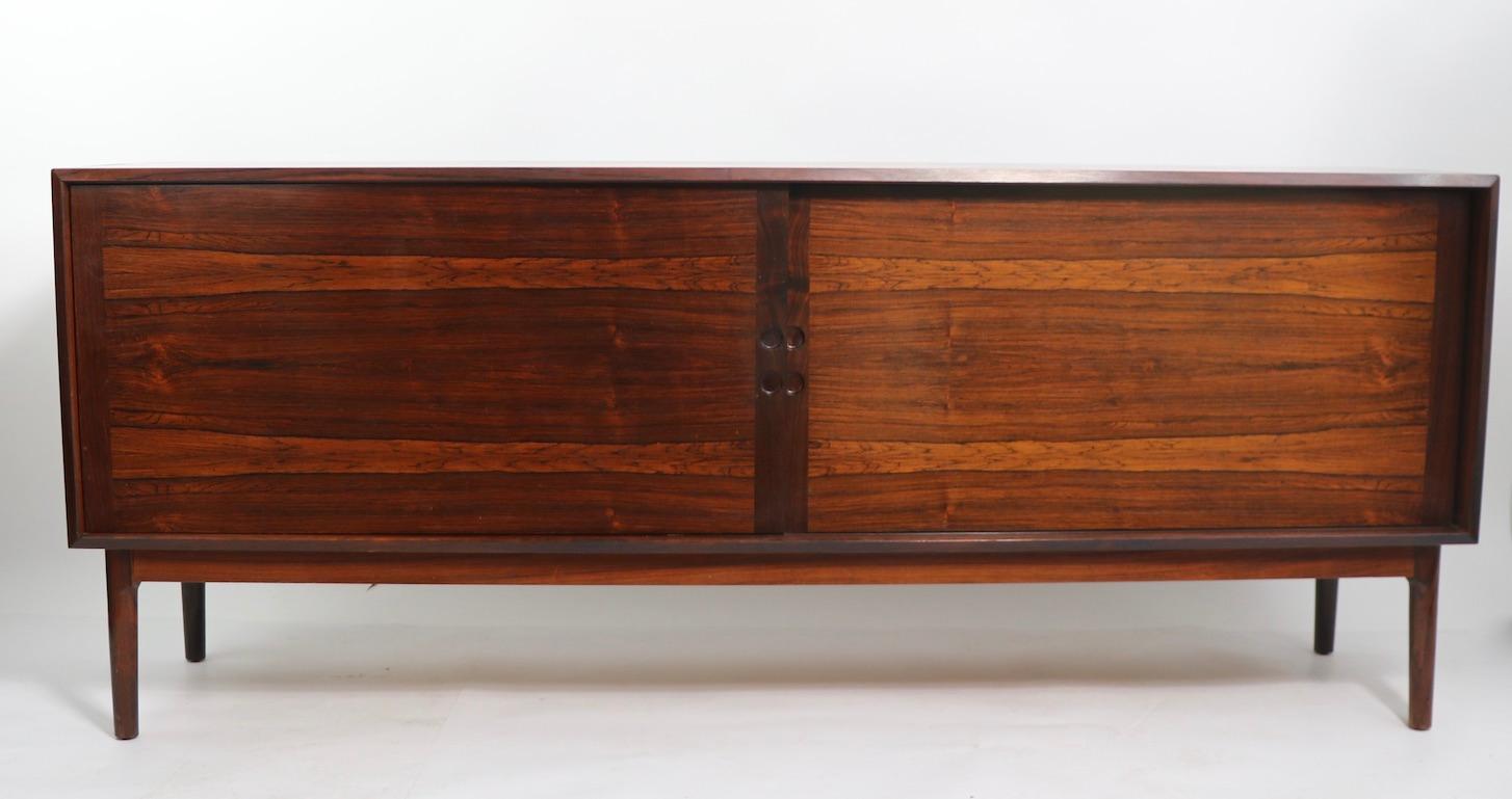 Stunning midcentury Danish modern style credenza having two sliding doors, which open to reveal shelved storage space, flanked by storage with interior drawers. Sophisticated, elegant, architectural design, in very fine original ready to use