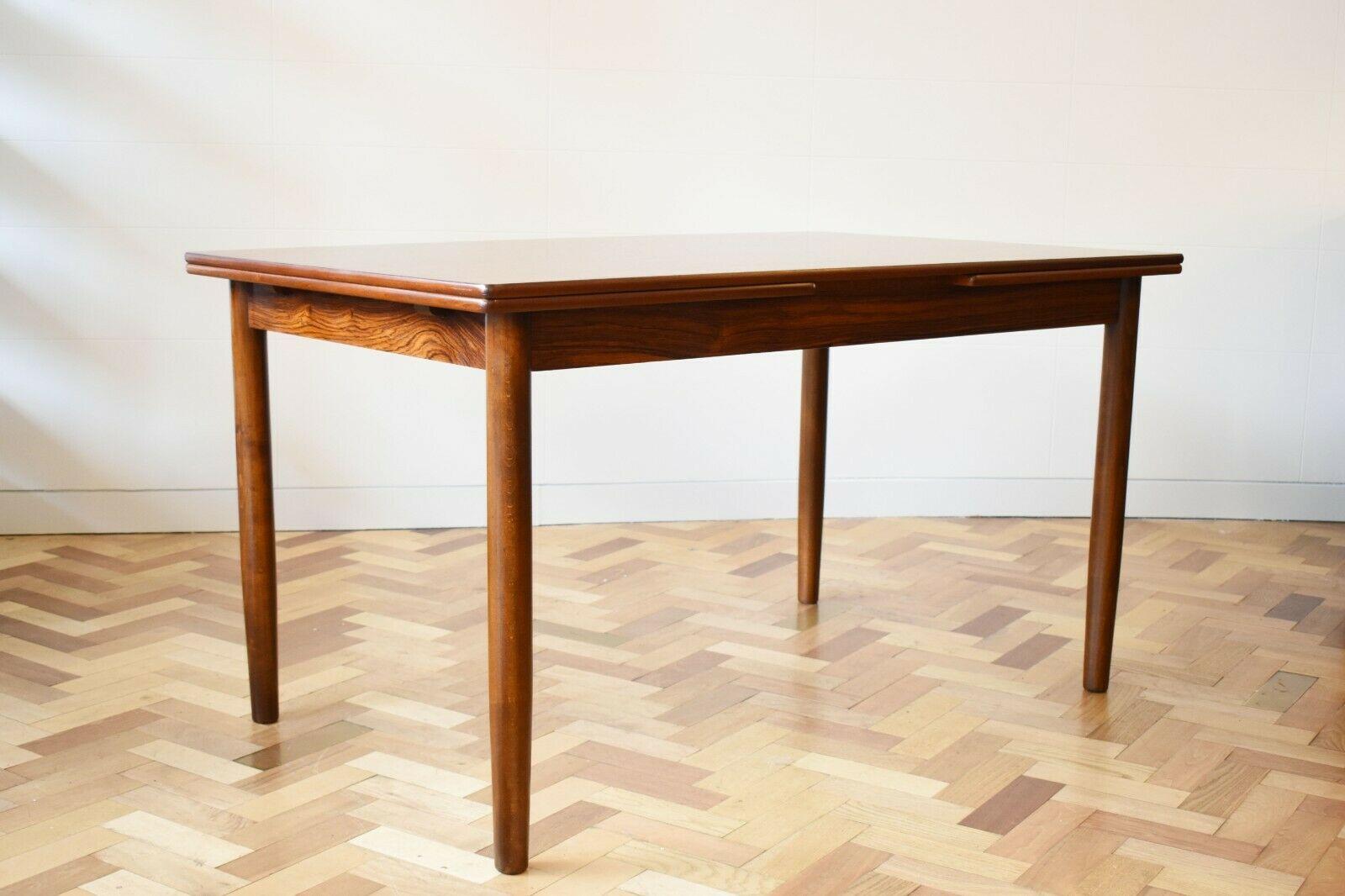 1960's Danish rosewood extendable dining table, set on tall thin legs. Elegant and sleek, the wood is in beautiful condition, and has been newly polished.