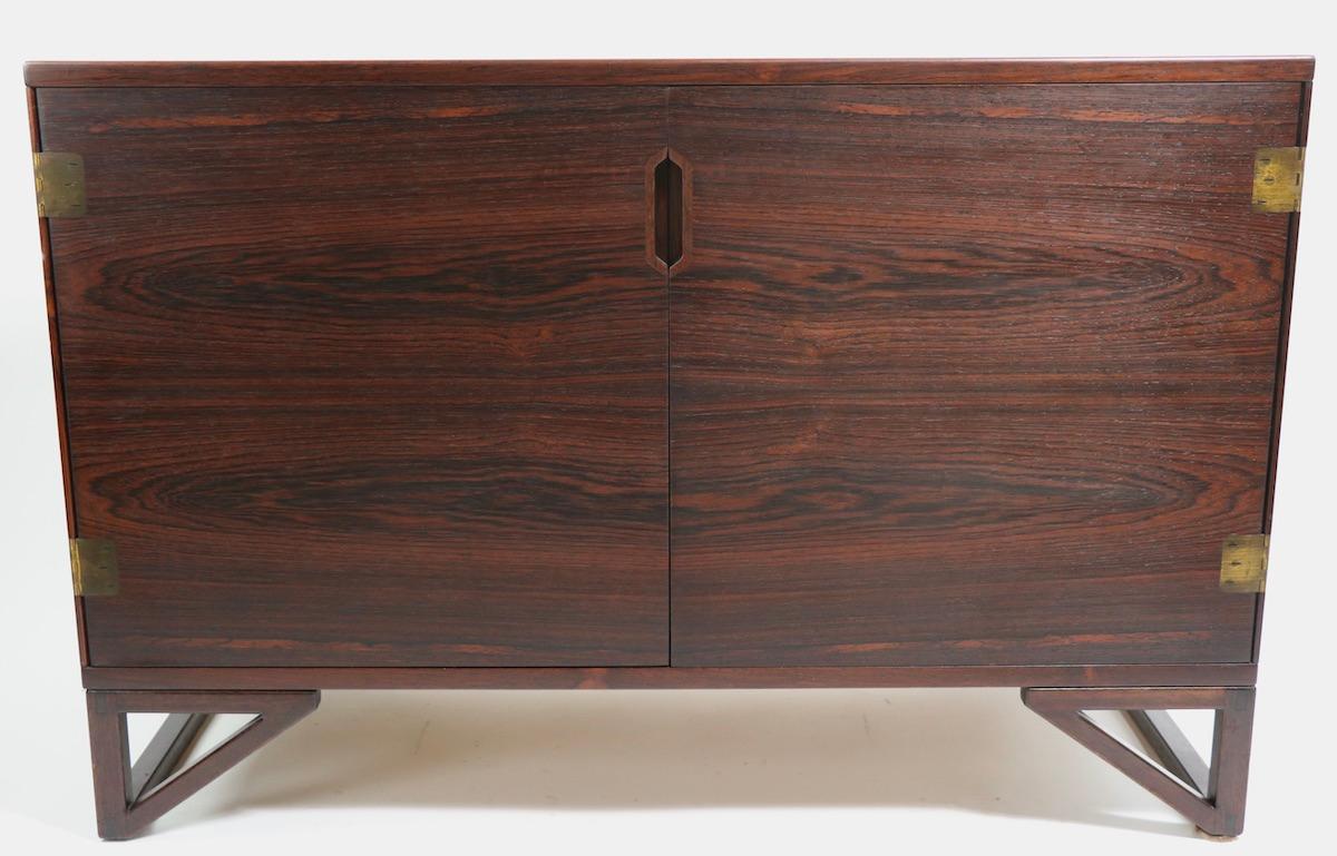 Very fine Danish Mid-Century Modern two cabinet in rosewood veneer with brass hinges. Designed by Svend Lankilde produced by Lankilde Mobler for Illums Bolighus. The doors open to revel interior drawers, flanked by shelved storage. This example is